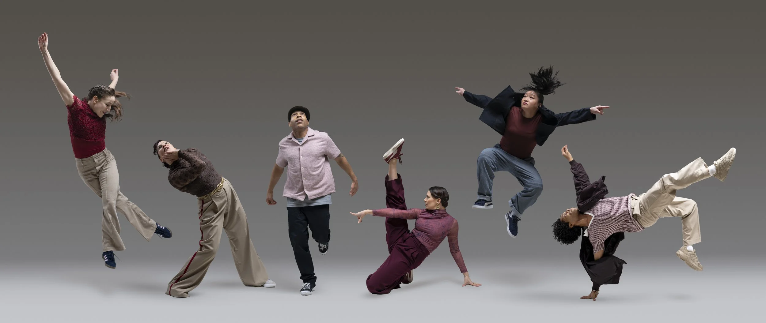 six dancers performing in front of a gray backdrop