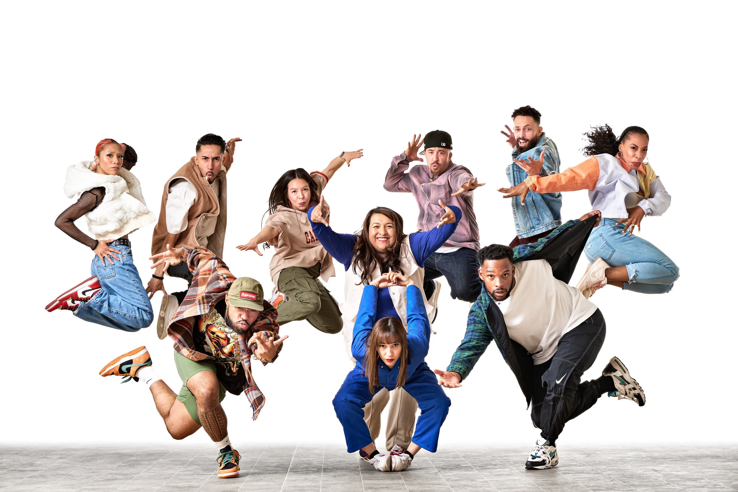 nine dancers posing midair in front of a white backdrop