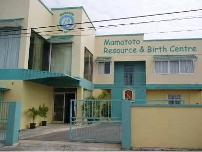 Exterior of Mamato resource and birth center with a blue gate and sign