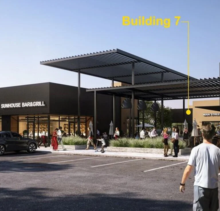 A modern shopping center with a restaurant named Sunhouse Bar & Grill on the left and a walkway leading to Building 7, with people walking around and parking spaces in front.