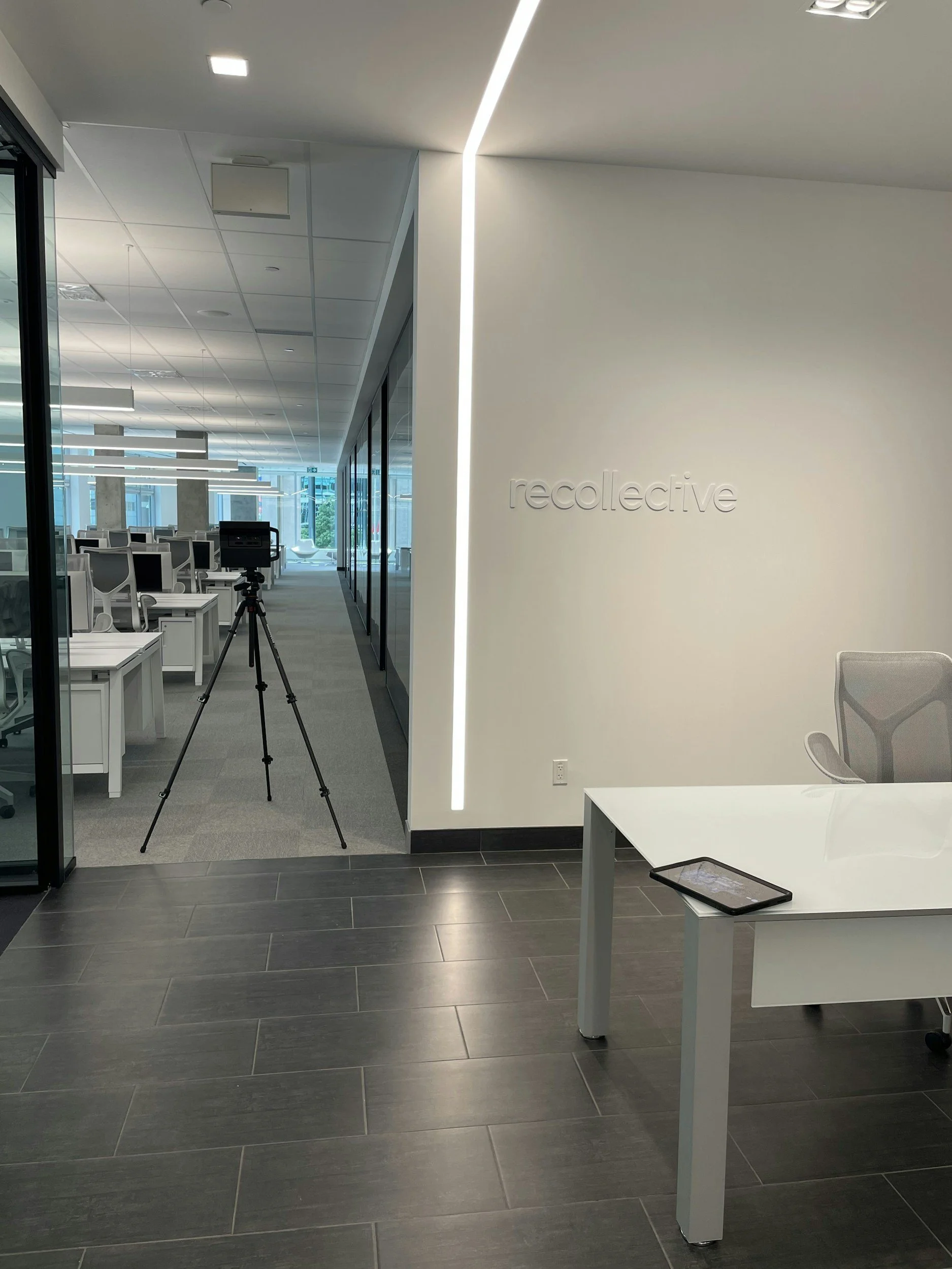 Modern office space with a reception desk, tablet, and seating area inside a corporate building.