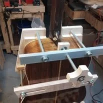 Woodworking lathe with a piece of wood mounted for turning, in a workshop setting.
