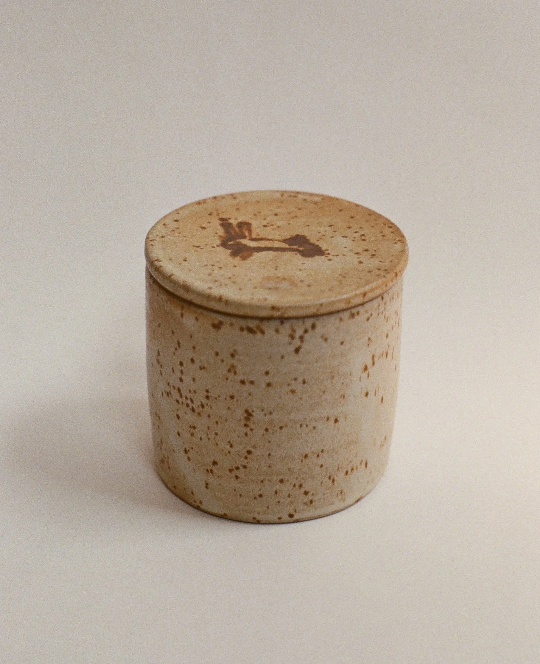 Close-up of a jar lid with a stopwatch design printed on top, against a plain light background.