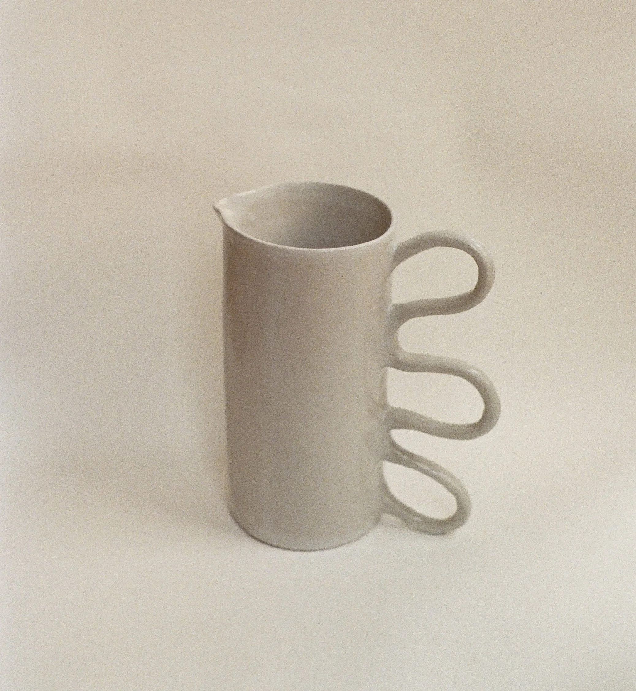 A white ceramic mug with the letters B M on it, against a plain light-colored background.