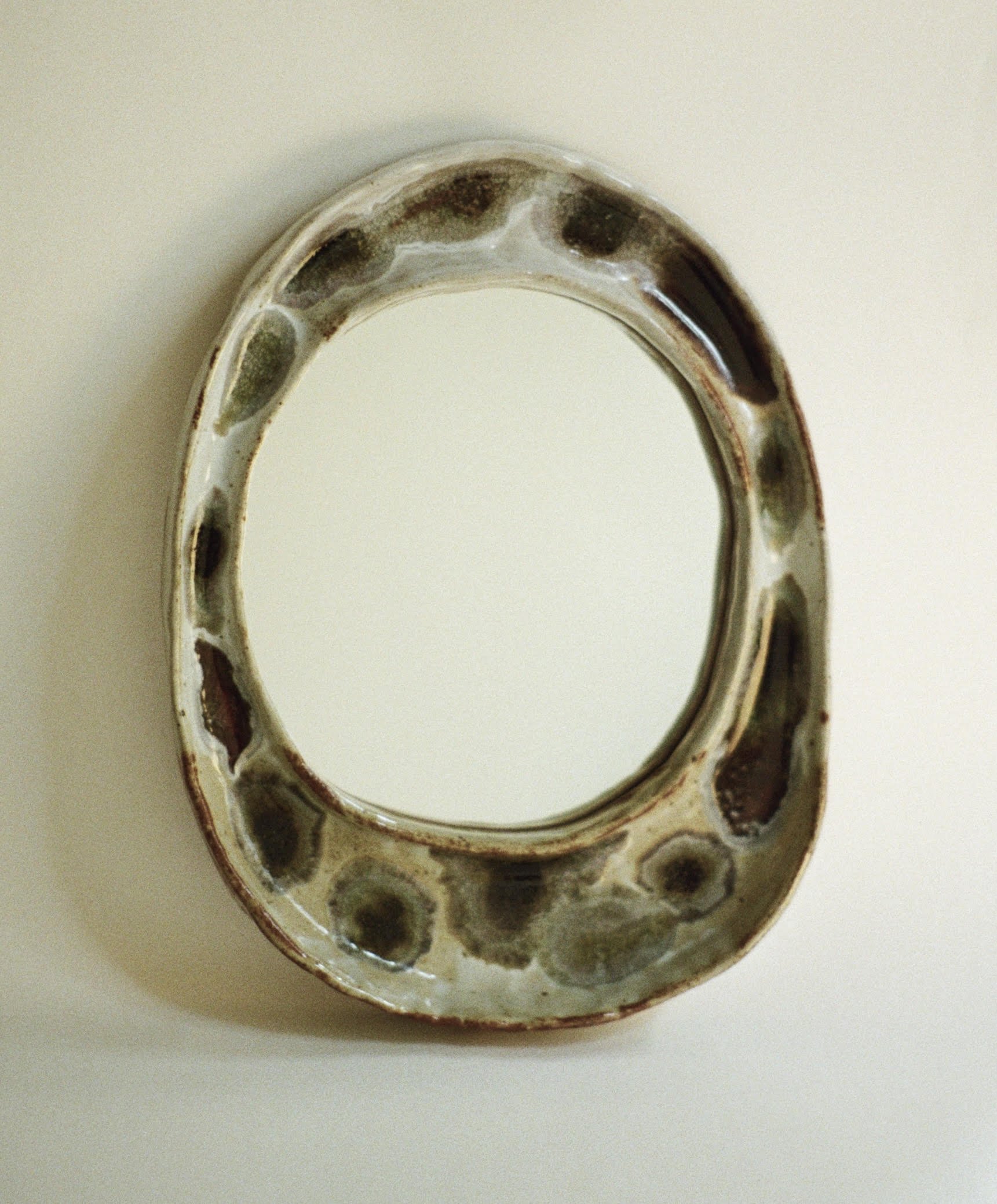 A close-up of a ceramic or metal ring with multiple circular holes around its perimeter, possibly a decorative object or part of a larger item, resting on a flat, light-colored surface.