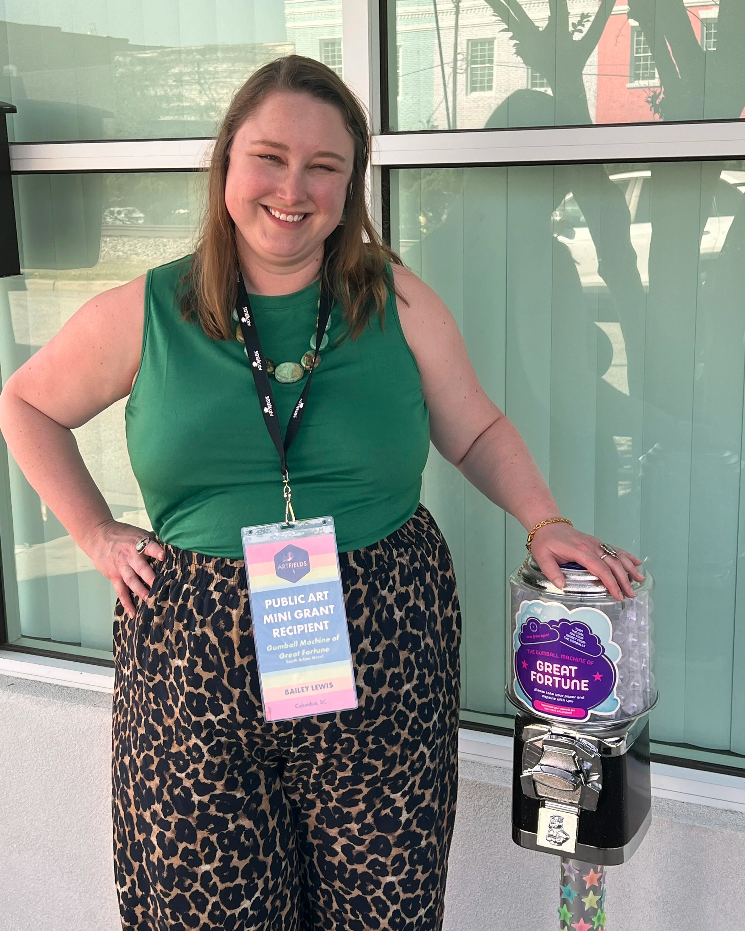 Author and interactive storyteller Bailey Lewis stands with her public art installation The Gumball Machine of Great Fortune at its installation at ArtFields 2026 where it received a public art grant.