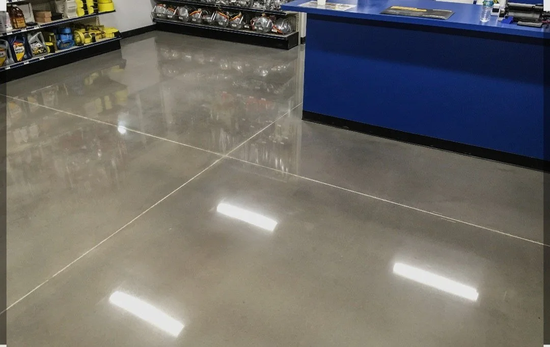 Polished concrete floor inside a hardware or automotive store with shelves of tools and equipment in the background.