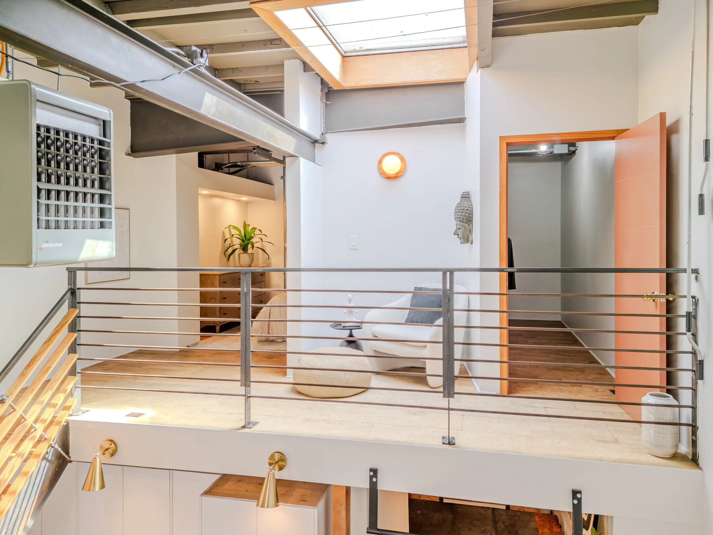 Interior of a modern house with a loft, white walls, wooden accents, potted plant, sculpture, and a staircase.
