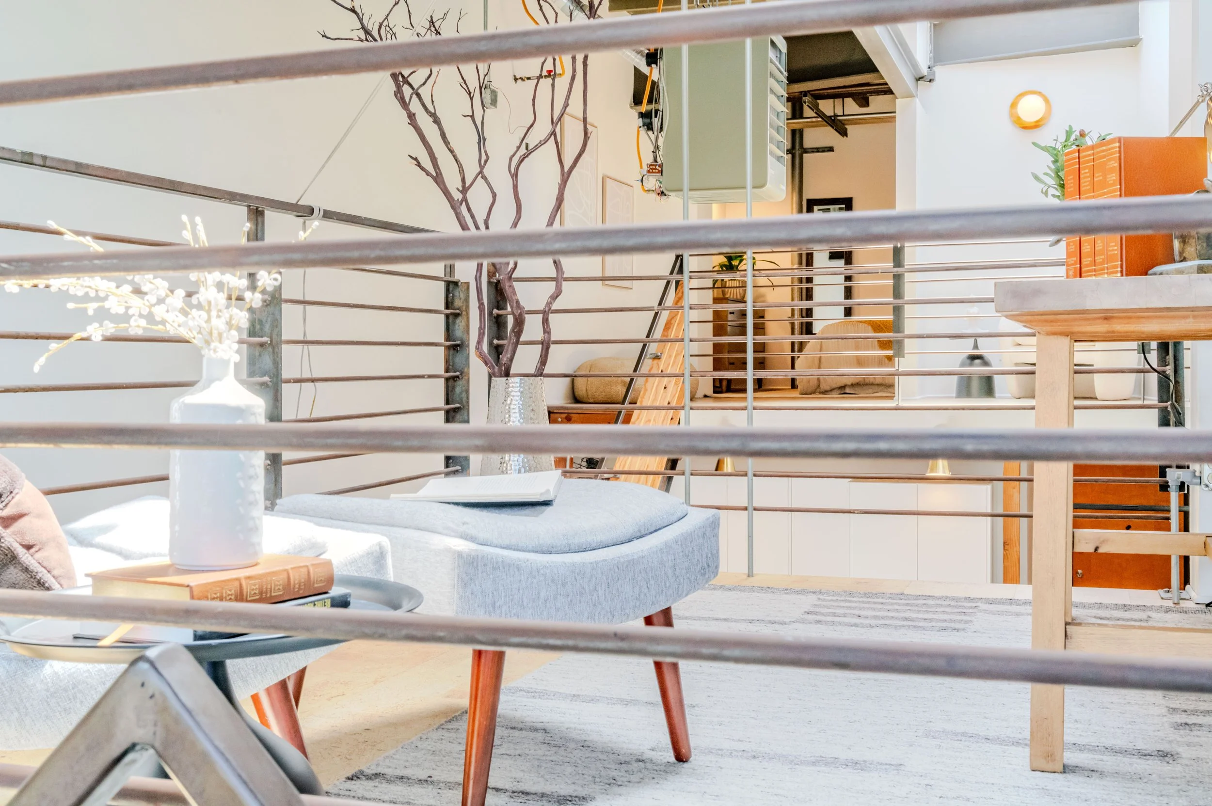 Living room with modern furniture and decorative items, viewed through metal railing.