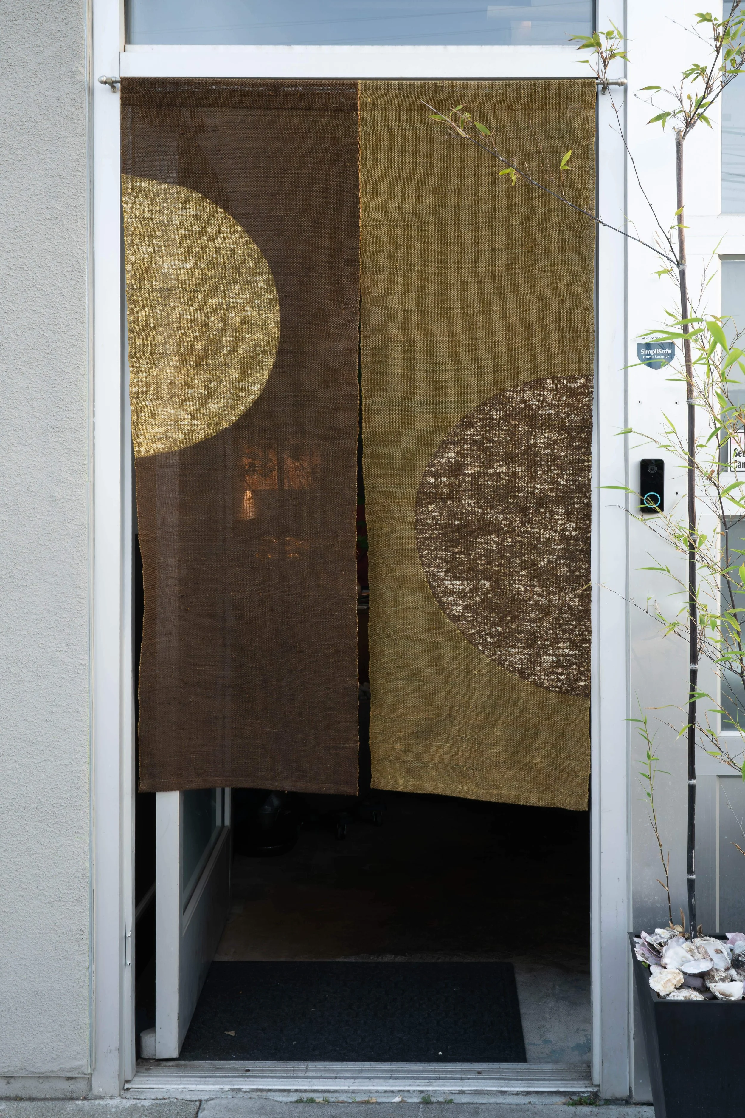 The image shows an open front door with a decorative curtain featuring large circles, partially revealing the interior and some plants outside.