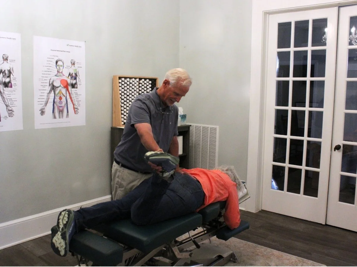 Dr. Baker using muscle testing to identify body imbalances