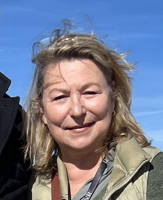 Ein Foto einer Frau mit blondem Haar im Freien bei blauem Himmel.
