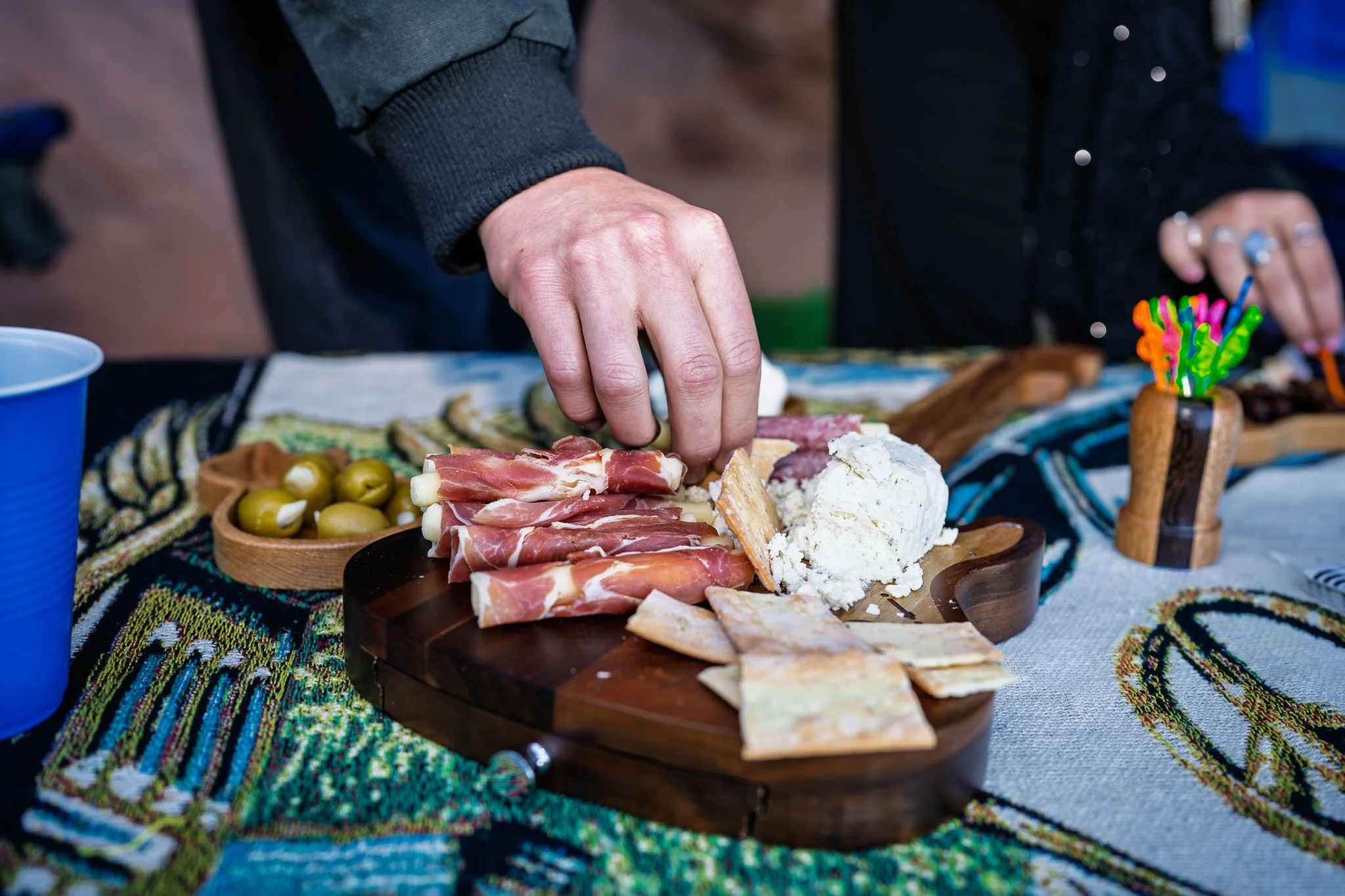 Private ride guests reaching for the charcerterie board at their private group tailgate at Red Rocks Amphitheatre before the show starts.