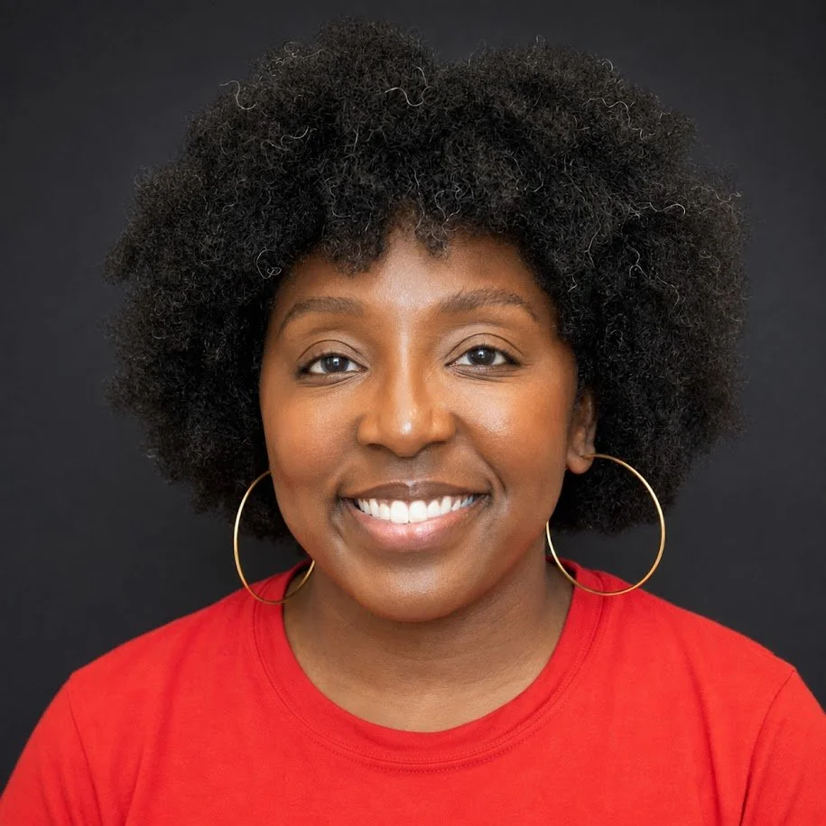 Portrait of a smiling Black woman with natural curly hair, wearing large hoop earrings and a red top, against a black background.