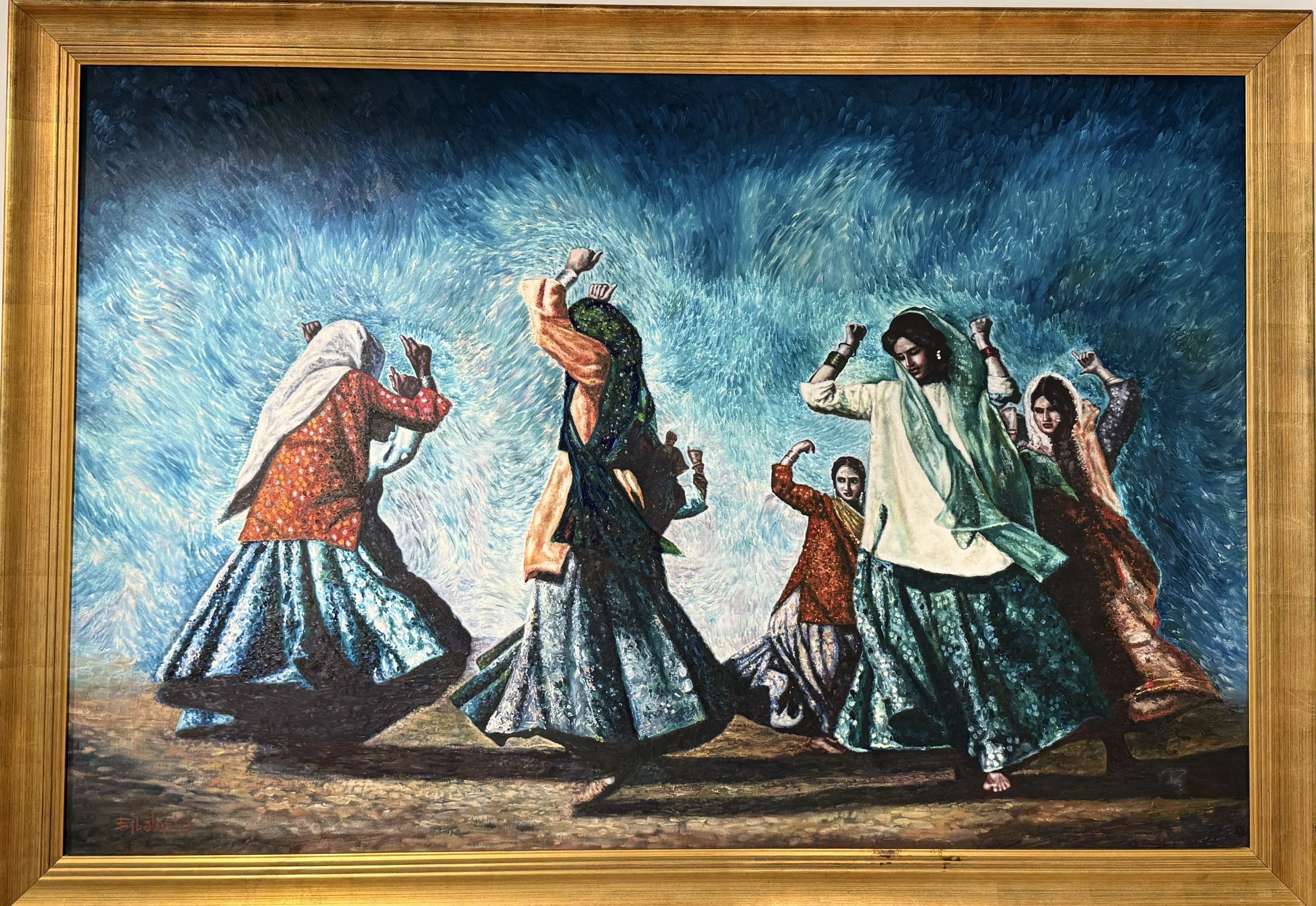 Painting of a group of women dancing in colorful traditional dresses, surrounded by a swirling blue background, framed in wood.