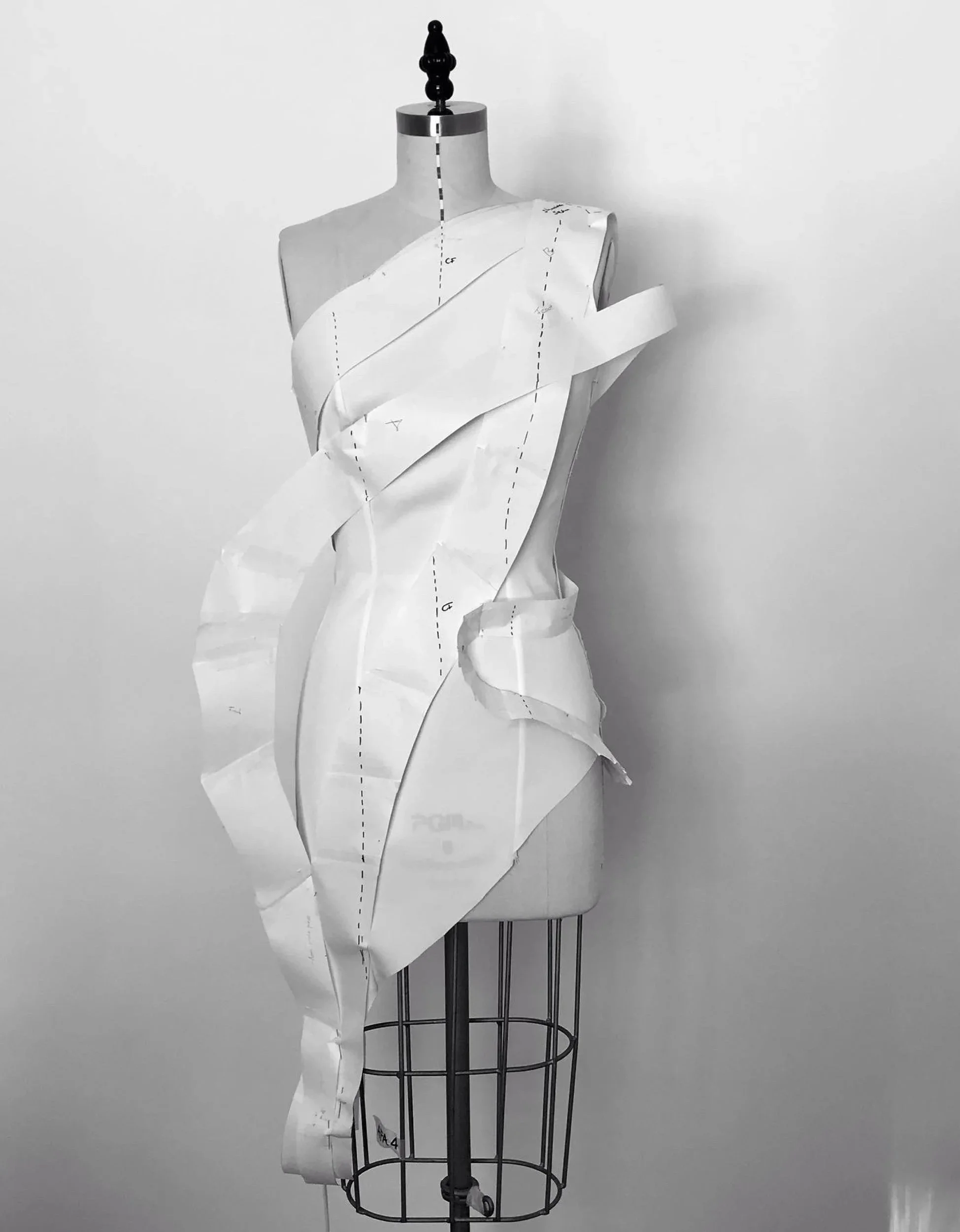 Ein auf einem Nähmodell stehender Schneiderpuppen mit Schnittmustern aus Papier, die über das Oberkörperteil gelegt sind.