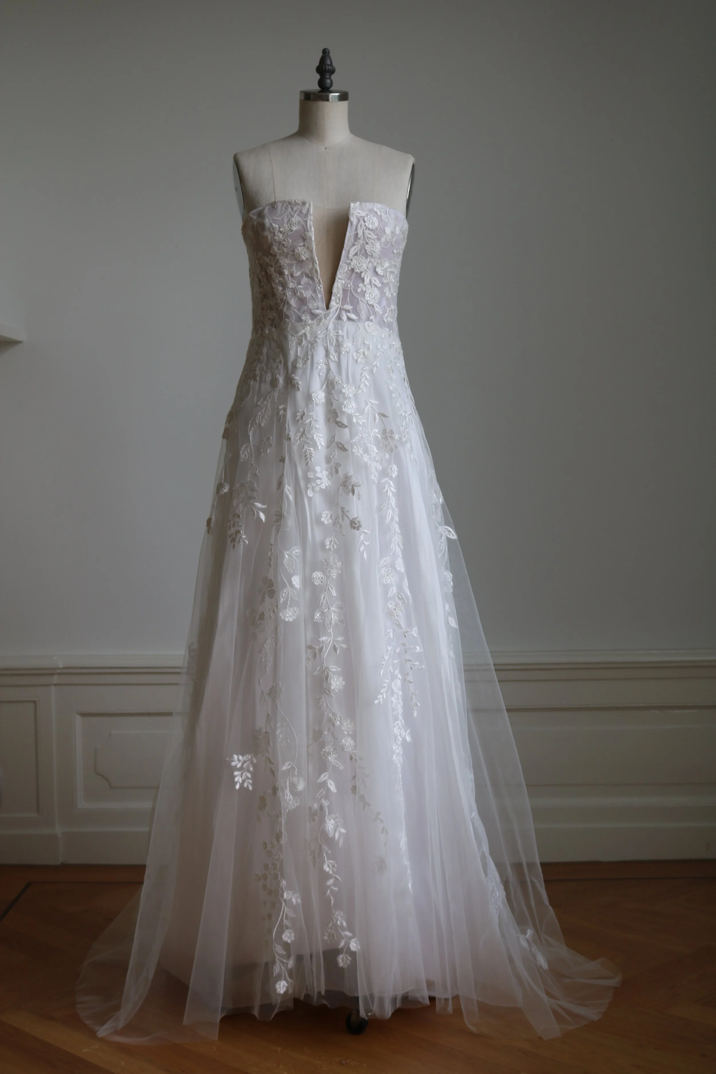 Weißes Brautkleid mit floraler Stickerei an einer Schneiderpuppe.