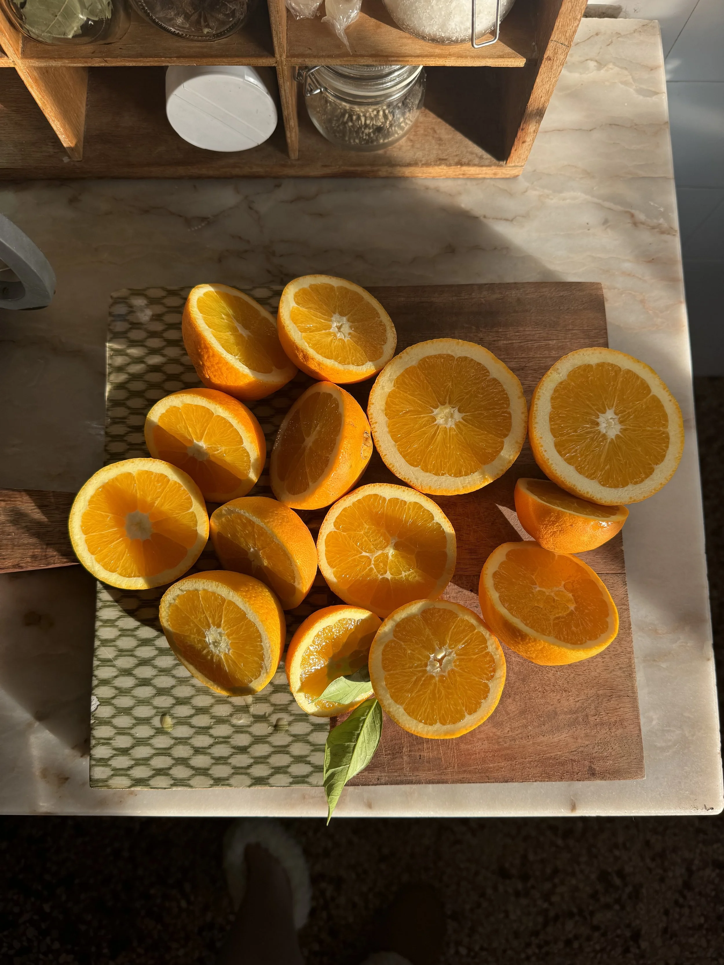 Sliced oranges arranged on a wooden cutting board on a kitchen counter.