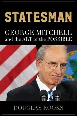 Statesman: George Mitchell and the Art of the Possible book cover. Text in gold and white on a black cover with author Douglas Rooks' name at the bottom. A photo of George Mitchell in glasses and a suit with a serious expression is on the cover.