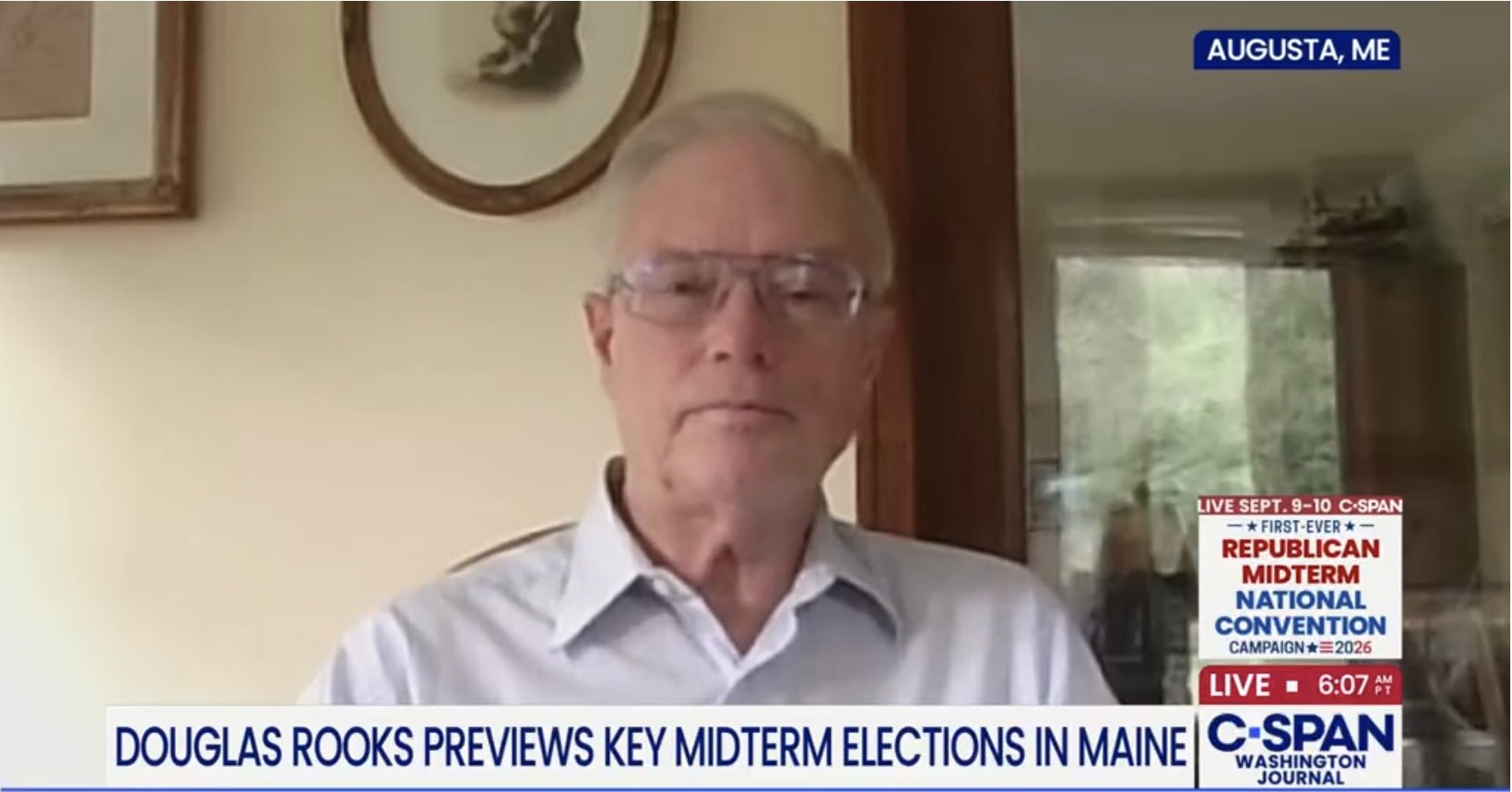 Douglas Rooks speaks to CSPAN from his home office. There are two pictures on the wall behind him and an open door show showing a windowed wall.