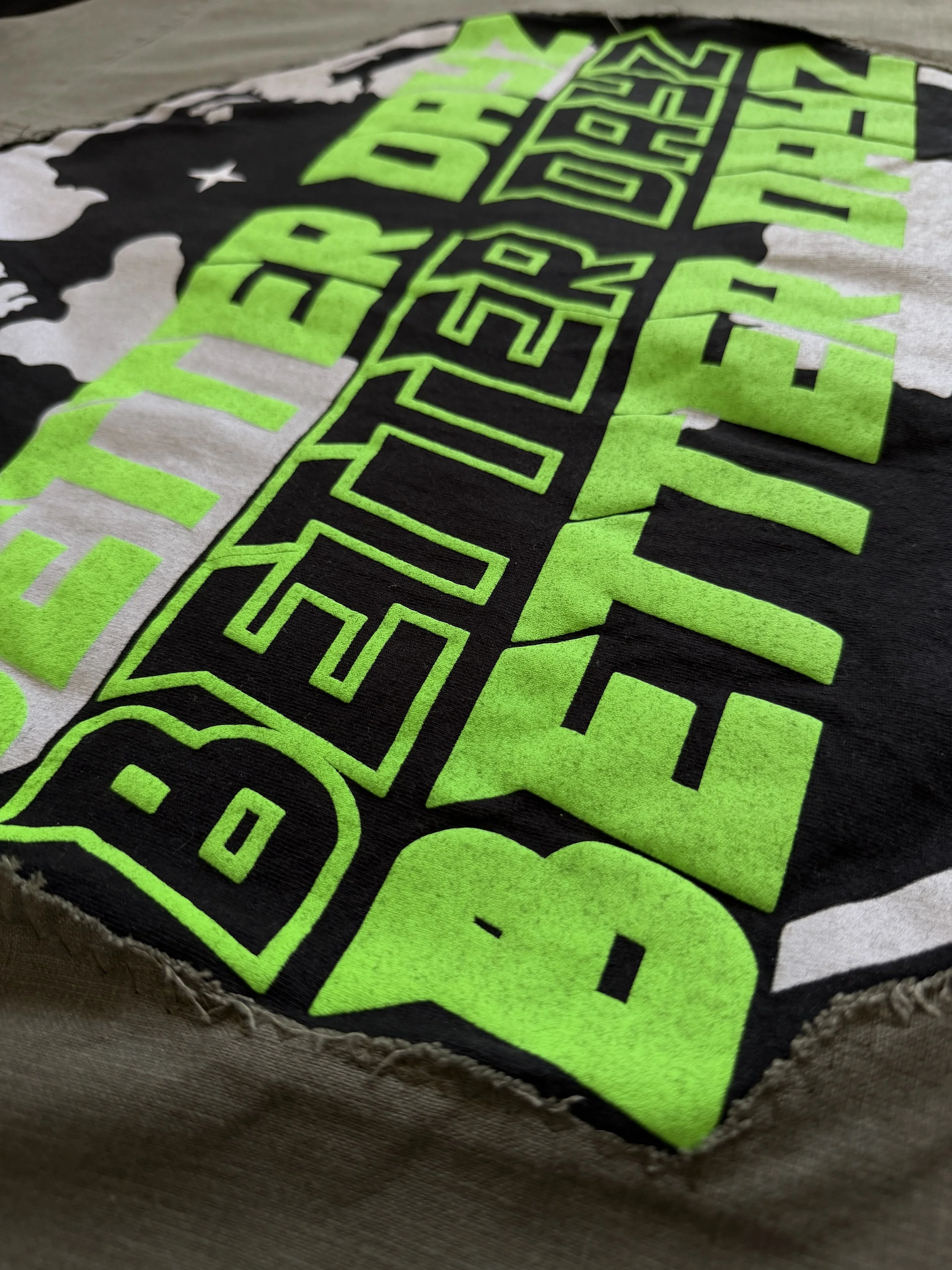 Close-up of a fabric patch with bright green and black design, featuring geometric shapes and text.