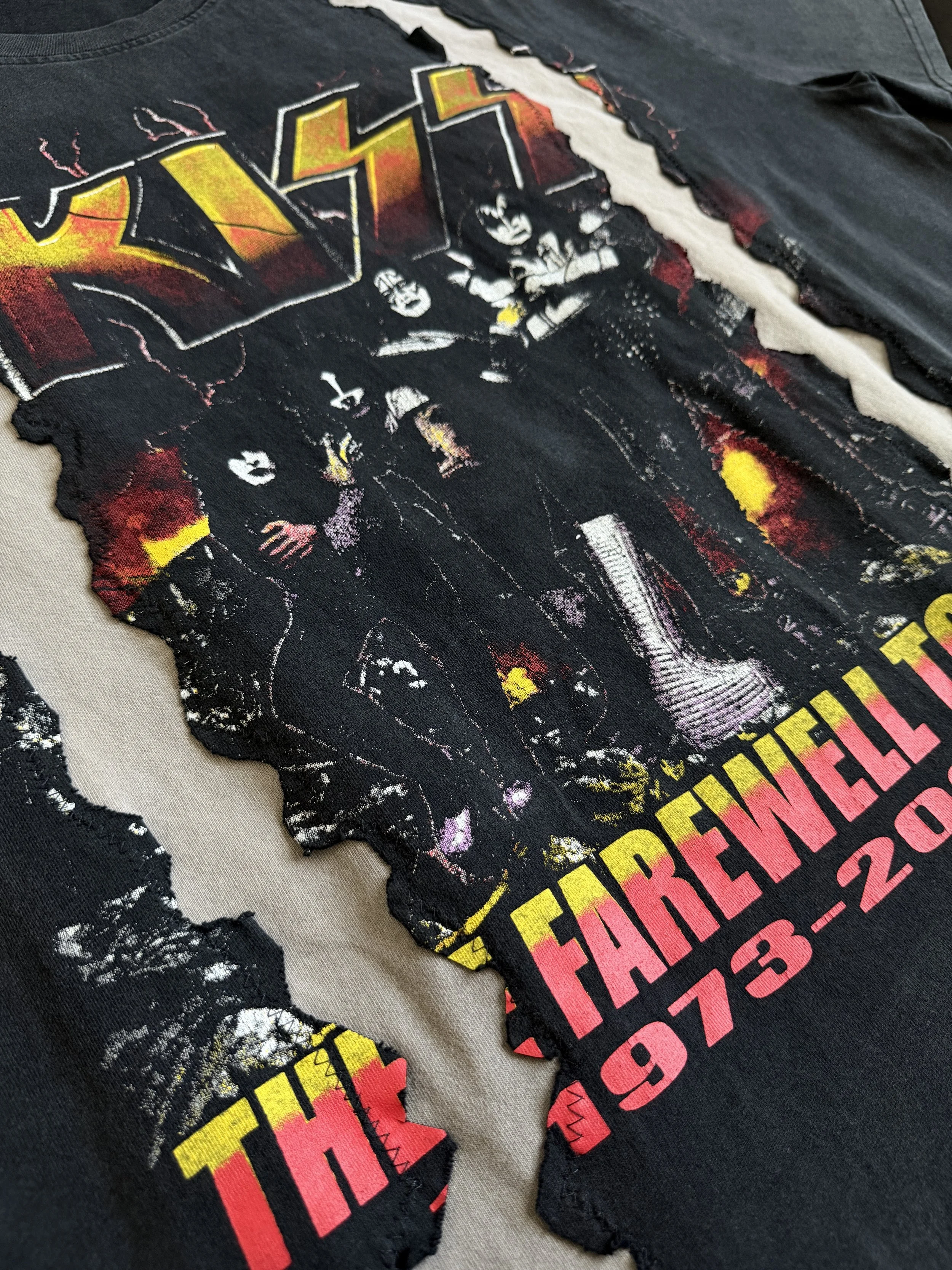 Close-up of a t-shirt with a distressed graphic design featuring the band KISS and their album 'Destroyer'. The shirt shows a torn and worn appearance with parts of the design and fabric frayed.