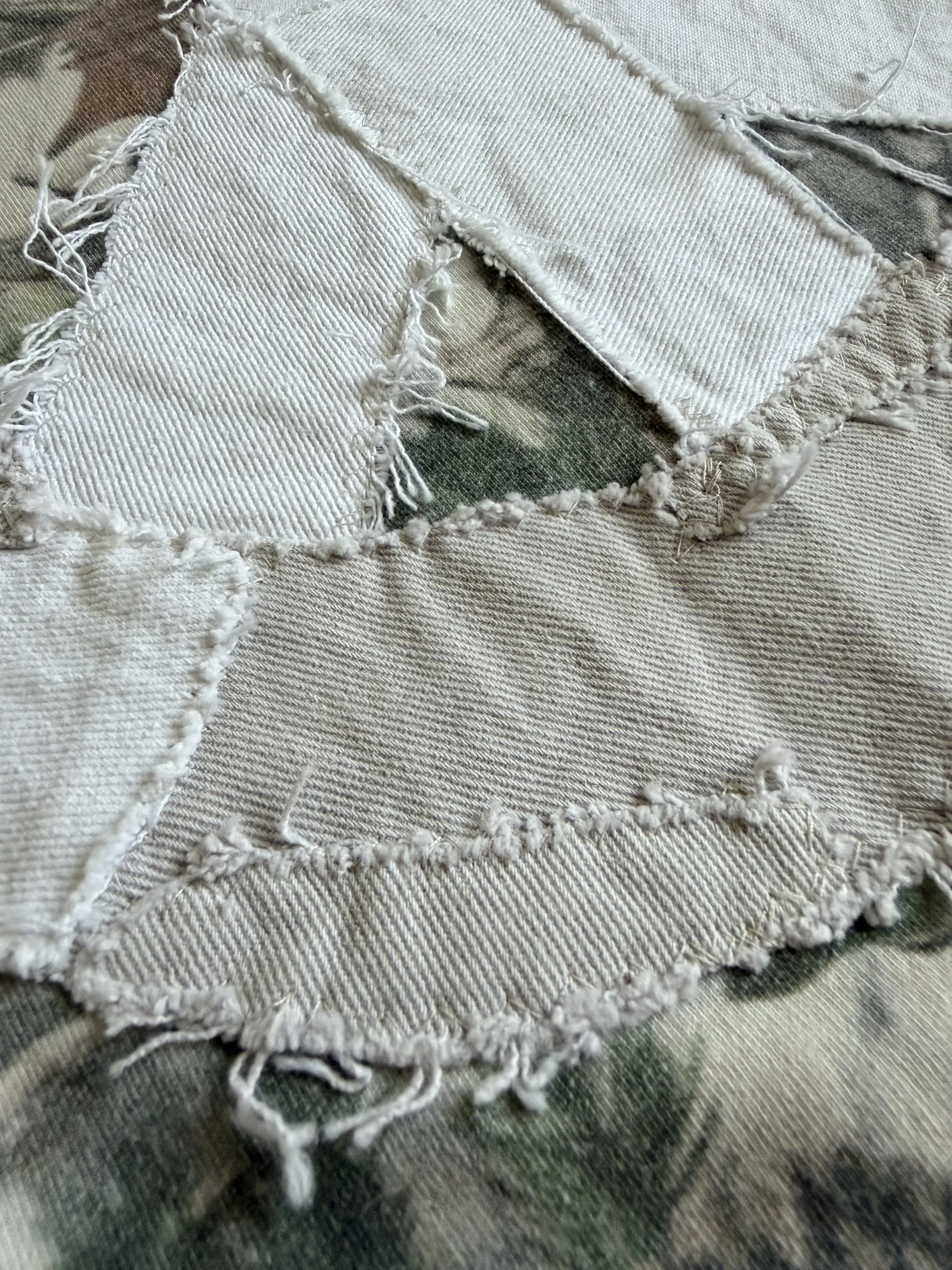 Close-up image of a piece of white denim fabric with frayed edges and torn sections.