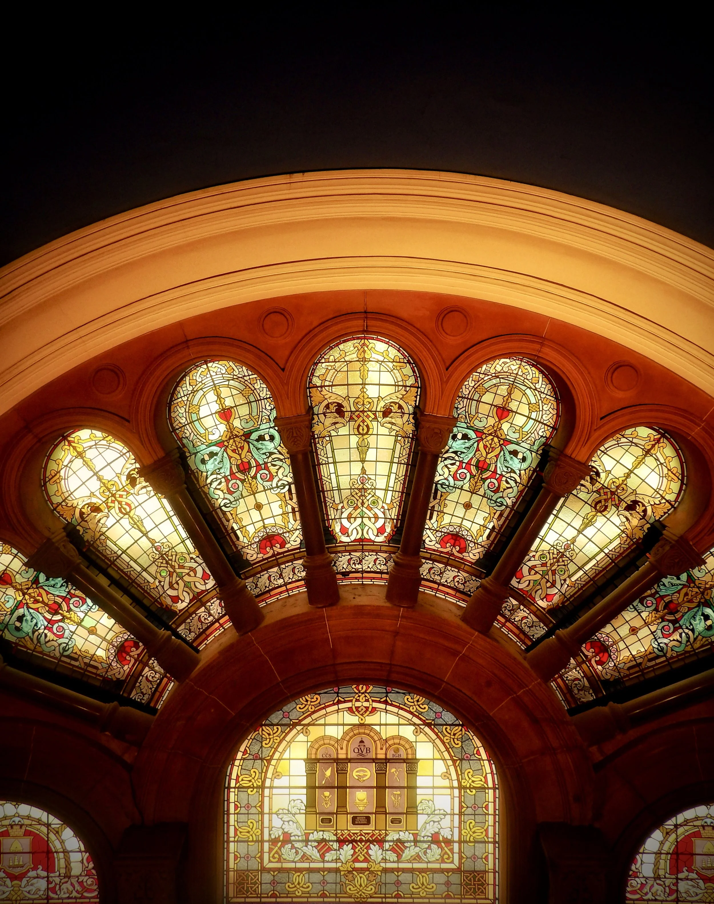 Interior view of a building with ornate stained glass windows and an arched ceiling.