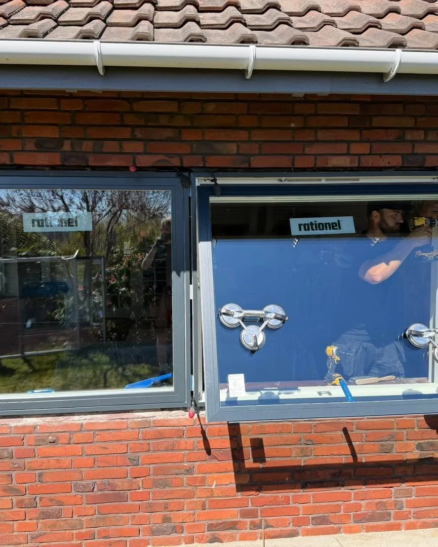 Vindue under installation eller reparation med værktøj og refleksion af en person, der tager billedet.