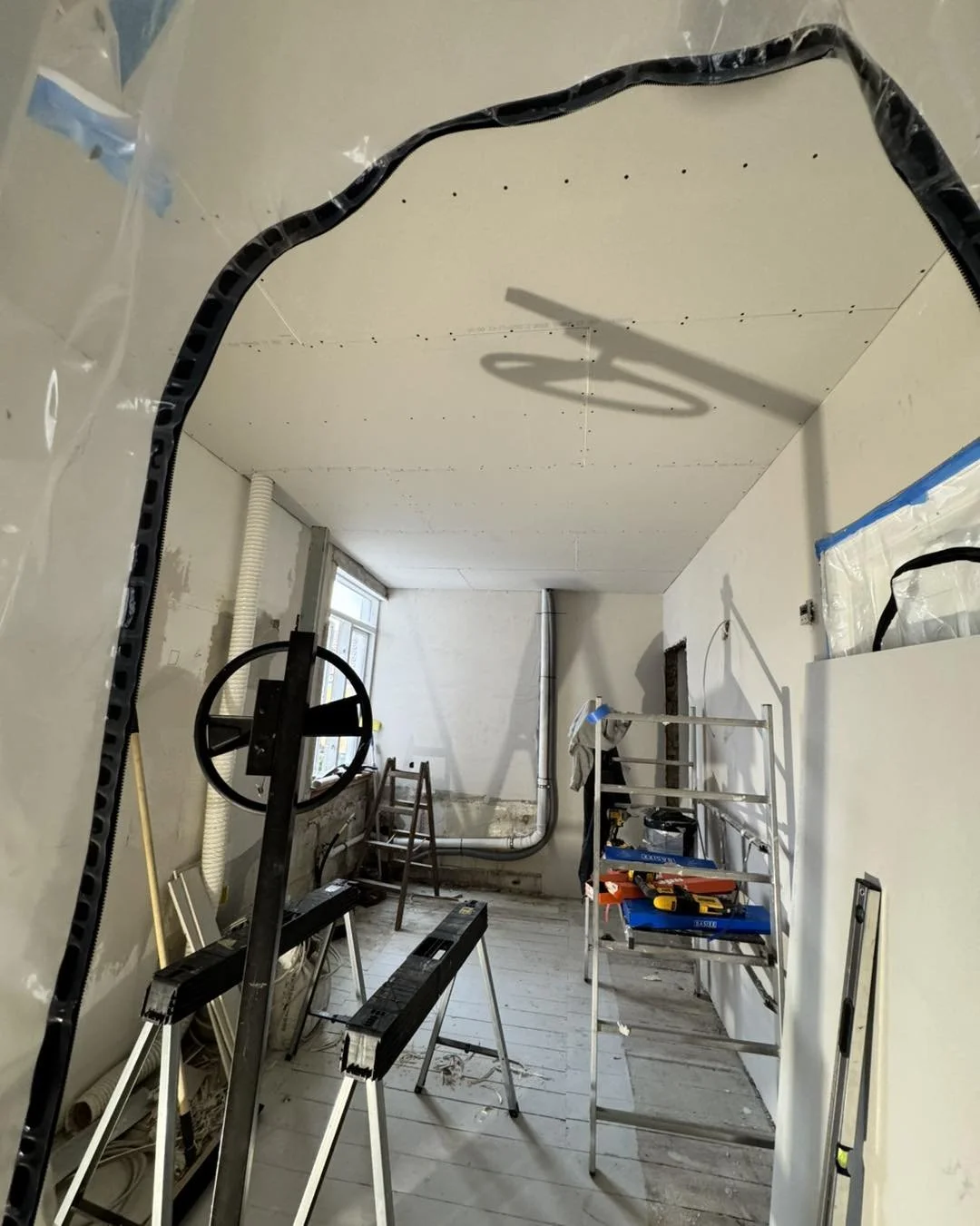 Indvendig af et rum under renovering med stilladser, værktøj og byggematerialer.