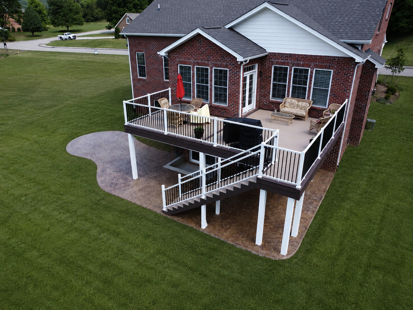 A complete outdoor living transformation featuring TimberTech AZEK Harvest decking with Kona accents, engineered LVL framing, integrated lighting, and a stamped concrete patio designed for functional year-round enjoyment