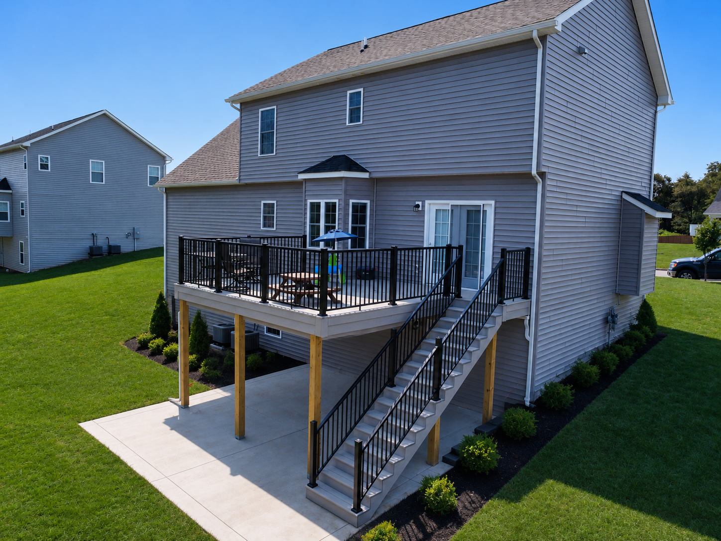 A functional and clean backyard transformation featuring TimberTech AZEK Landmark decking, oversized patio space, integrated drainage systems, and a modern black aluminum railing package designed for everyday outdoor living.
