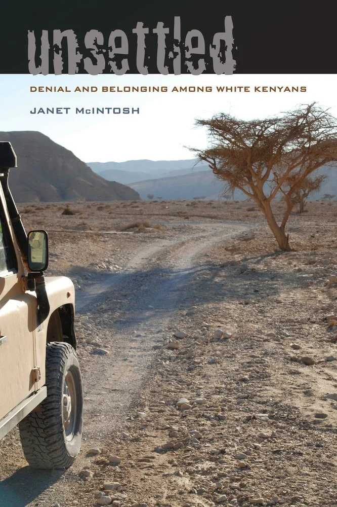 The cover of a book titled 'Unsettled: Denial and Belonging Among White Kenyans' by Janet McIntosh. The image shows a desert landscape with a dirt road, a partial view of a beige off-road vehicle on the left, and a solitary leafless tree on the right, with distant mountains in the background.