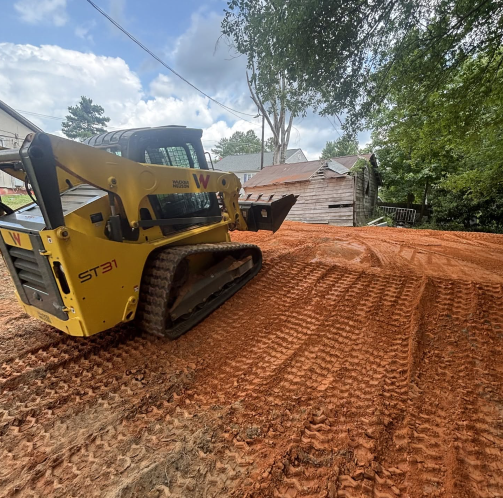 Skid steer performing land grading and site preparation on residential property for Palmetto South Construction