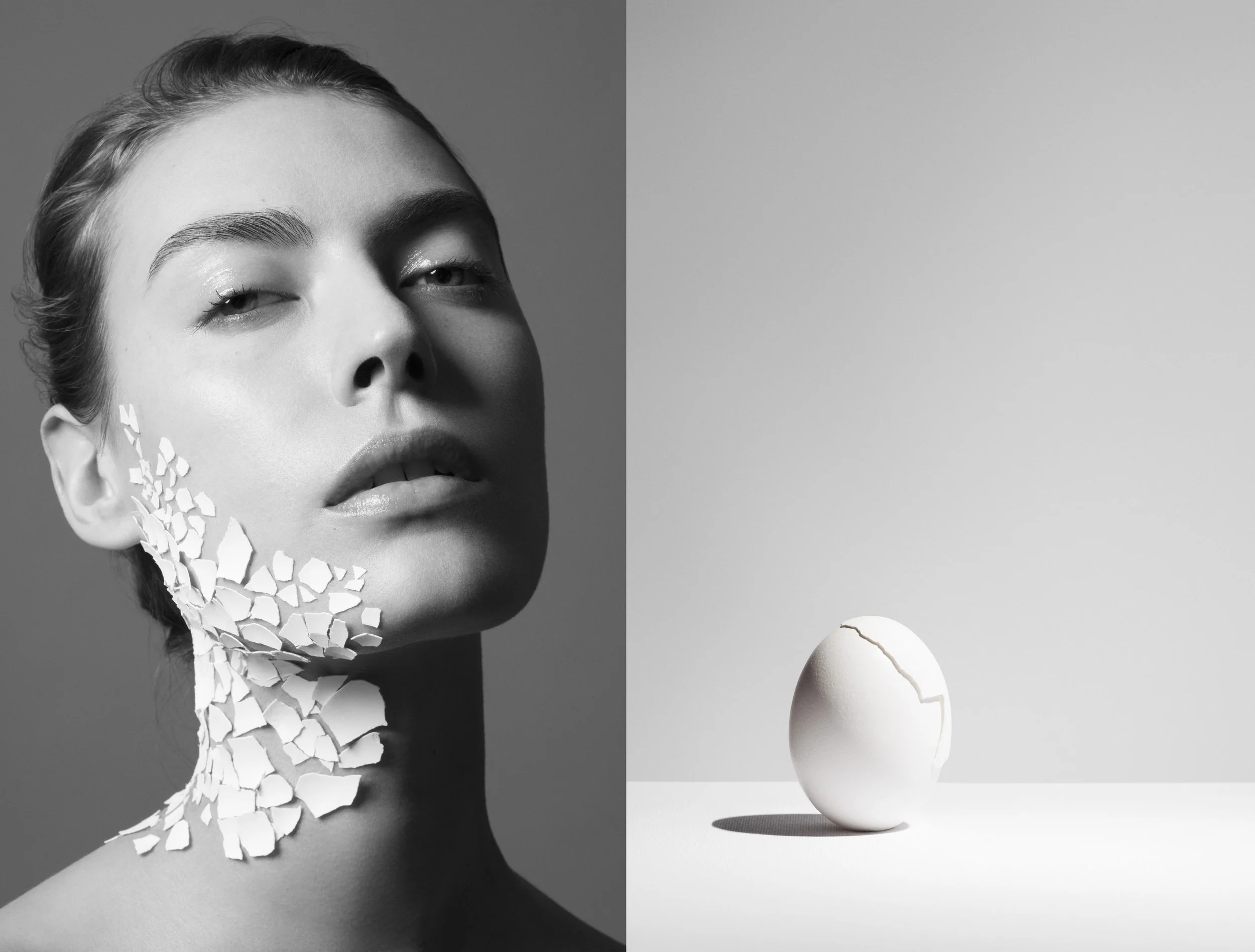 Portrait en noir et blanc d'une femme avec des morceaux de vaisselle cassée en cascade sur sa tête et son cou, à gauche. À droite, un œuf cassé et un œuf entier sur une surface plate dans un environnement minimaliste.