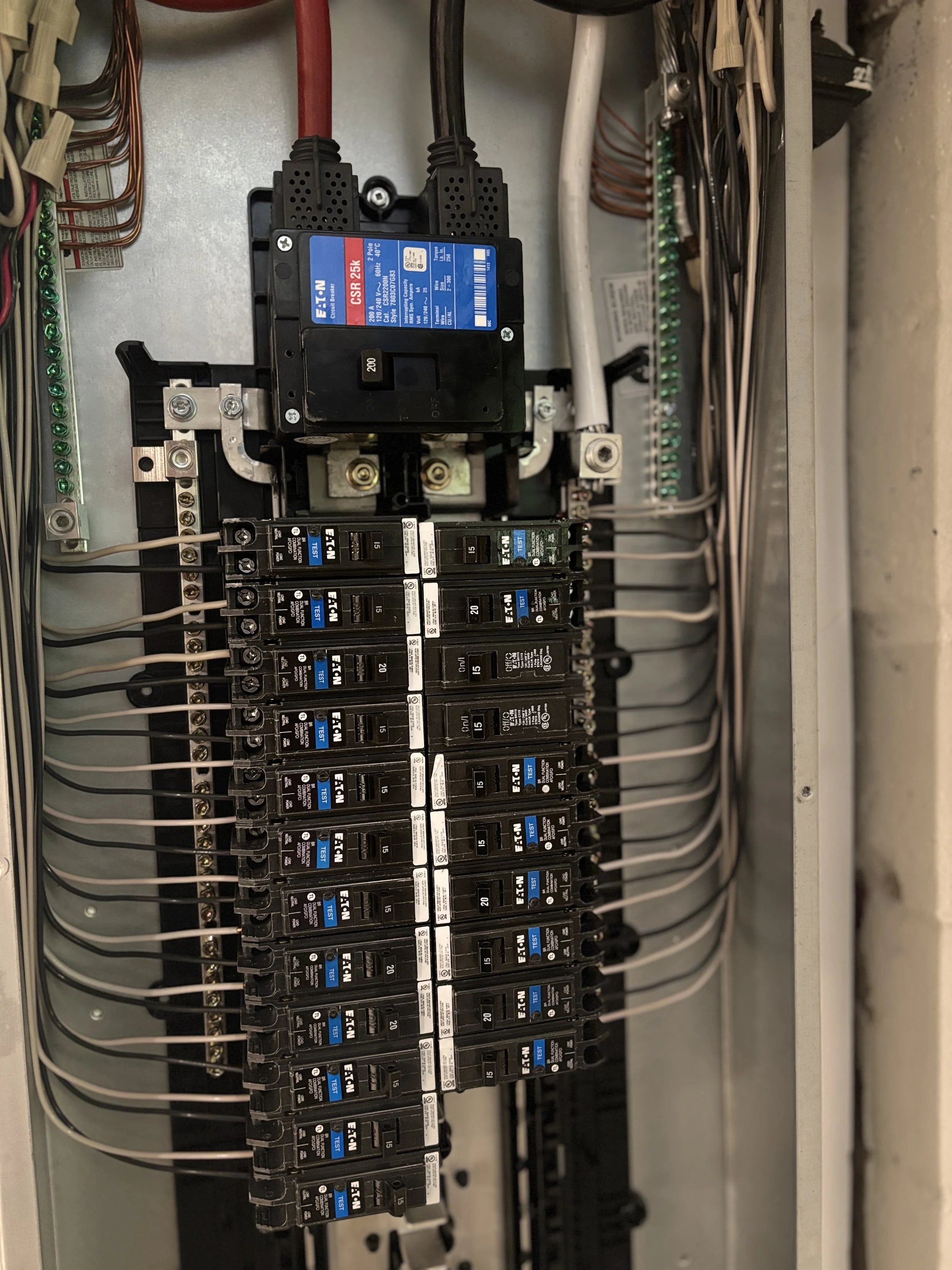 Inside view of an electrical breaker panel with multiple circuit breakers and wires.