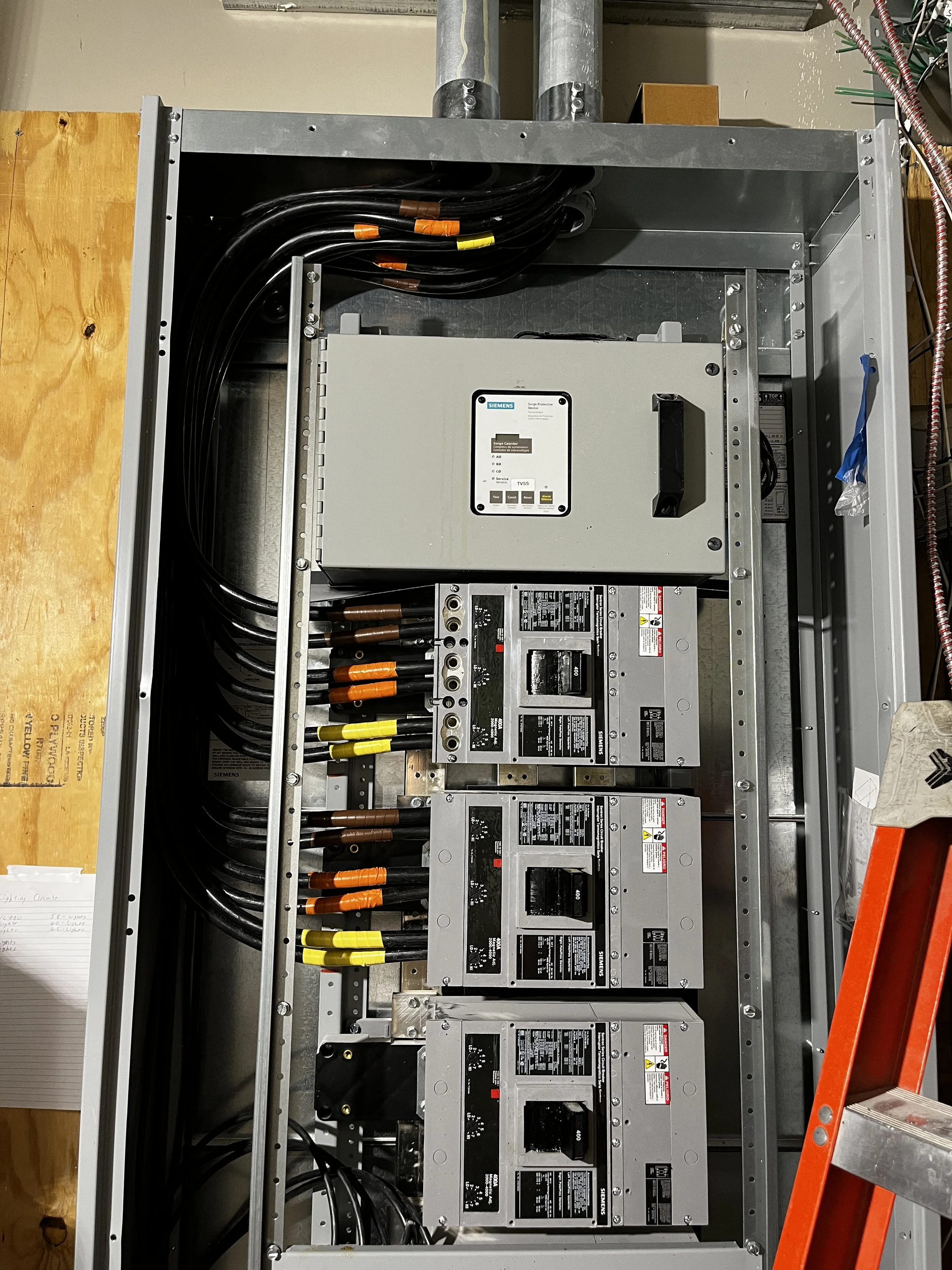 Electrical panel with Siemens equipment, circuit breakers, cables, and conduits.