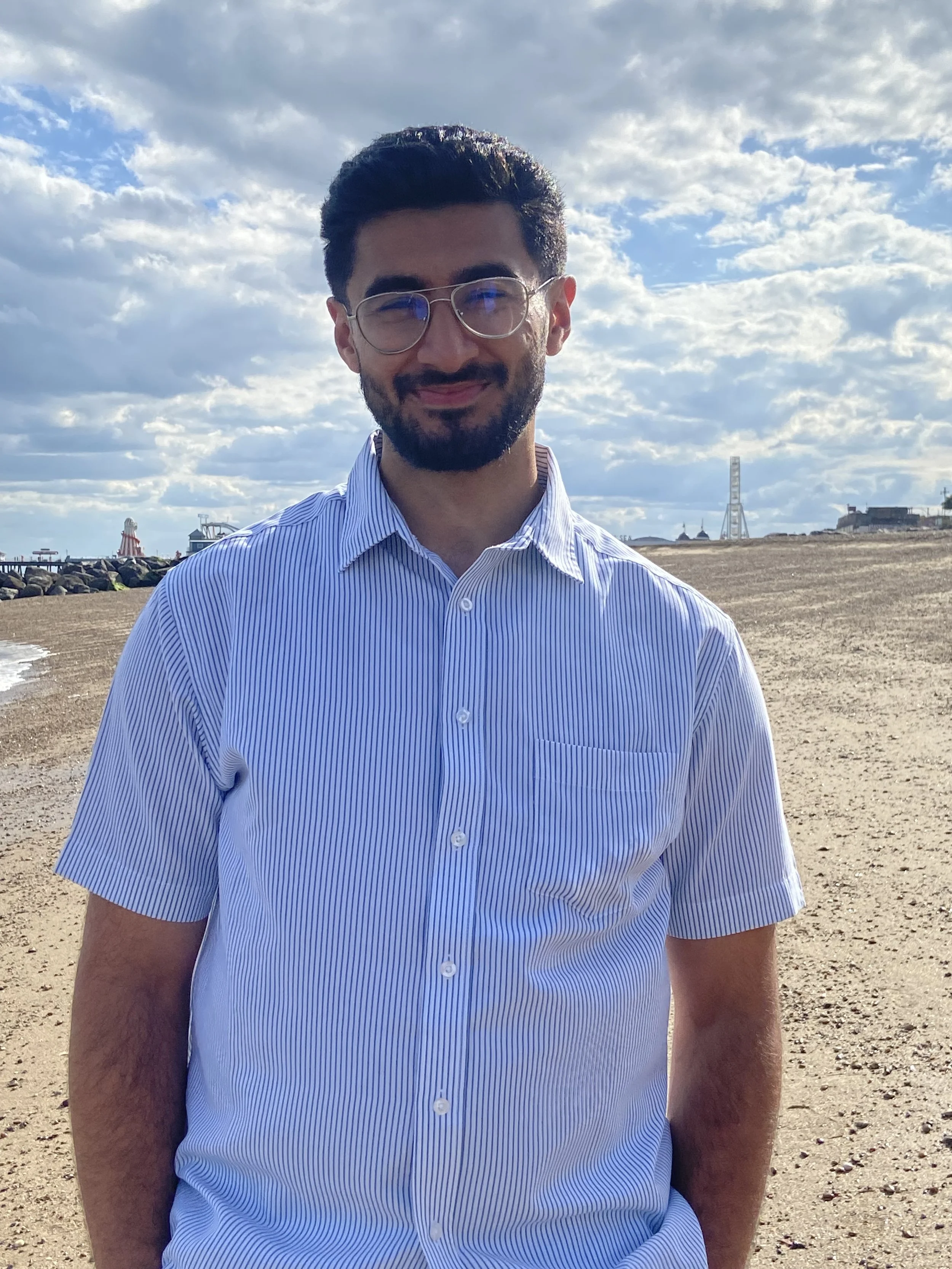 A friendly looking man with a beard and glasses at the beach.