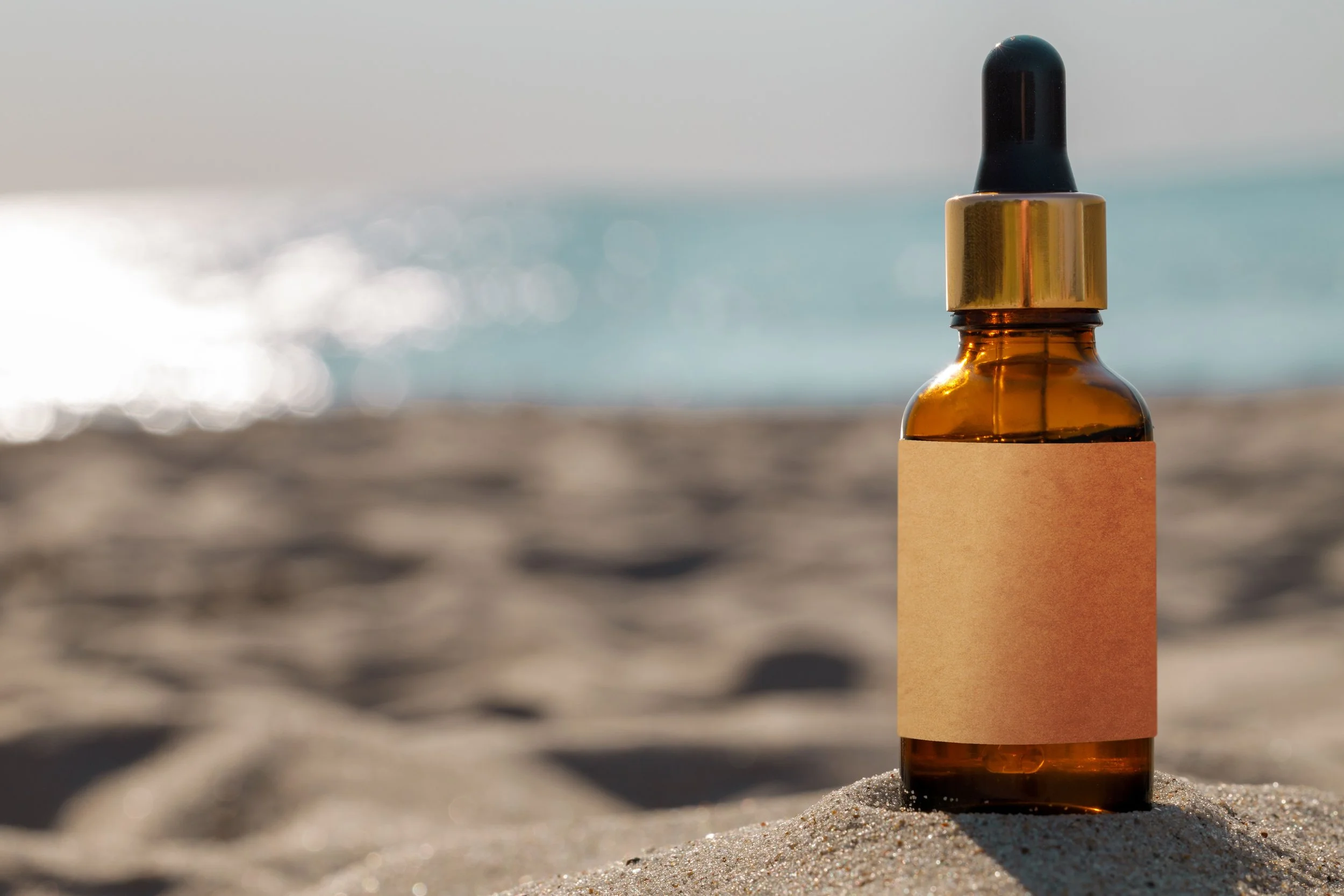 A dropper bottle with the beach in the background