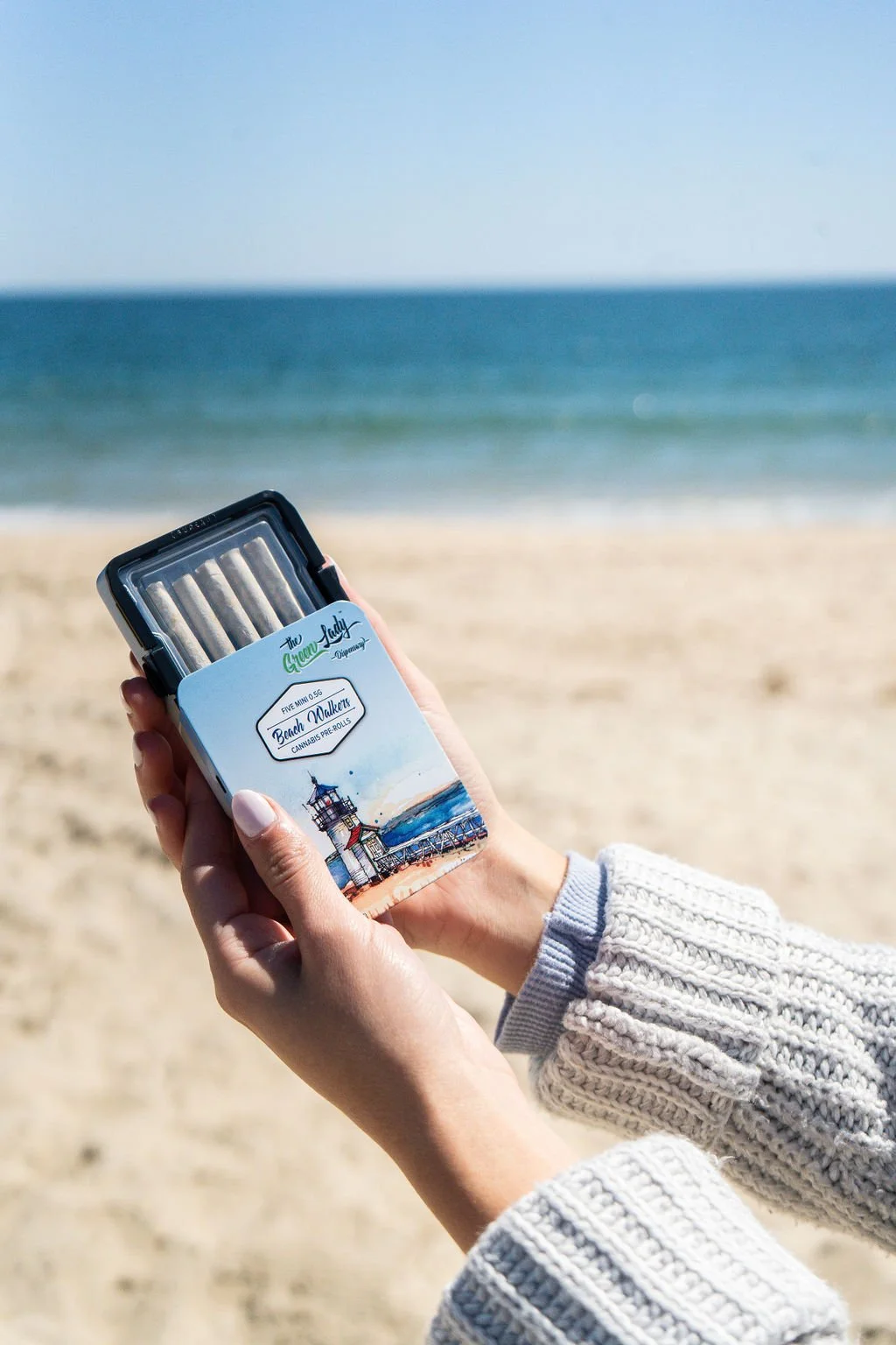 A woman on the beach holding a tin of beach walkers pre-rolls from The Green Lady Dispensary