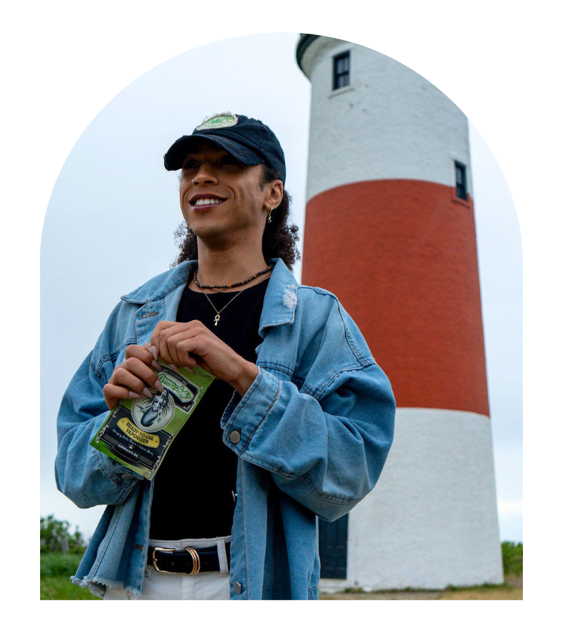 A person standing in front of a red and white lighthouse about to open a ready to use vaporizer pack from The Green Lady