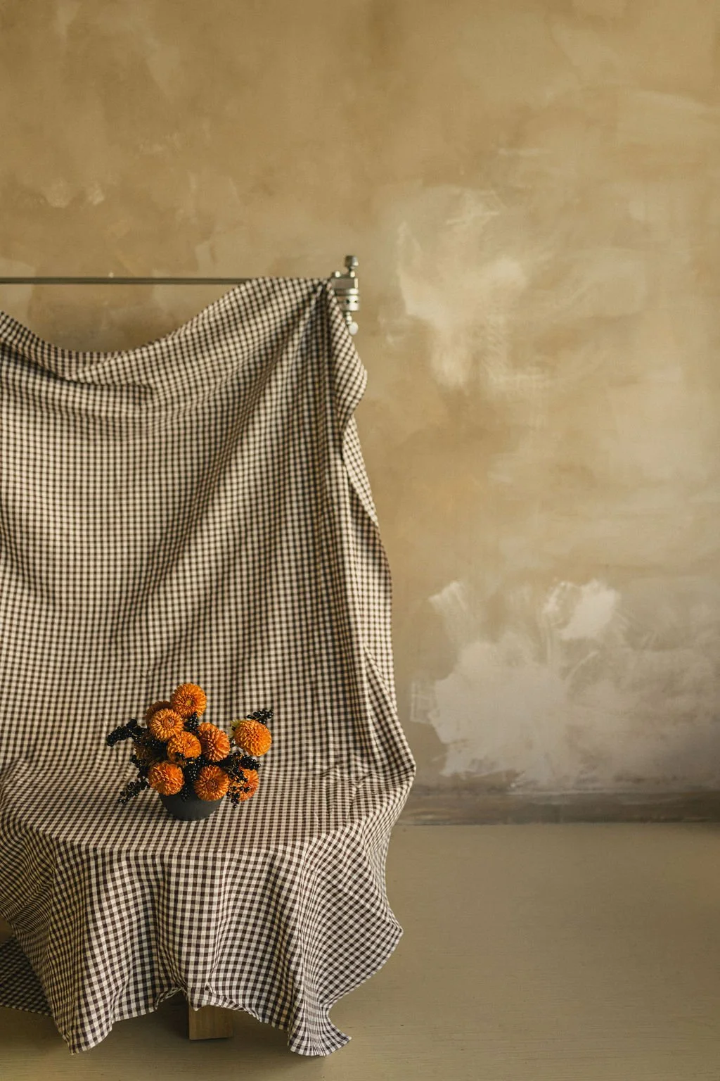 Dahlias on a gingham-draped table against a warm plaster wall, styled floral photoshoot in a Montréal studio
