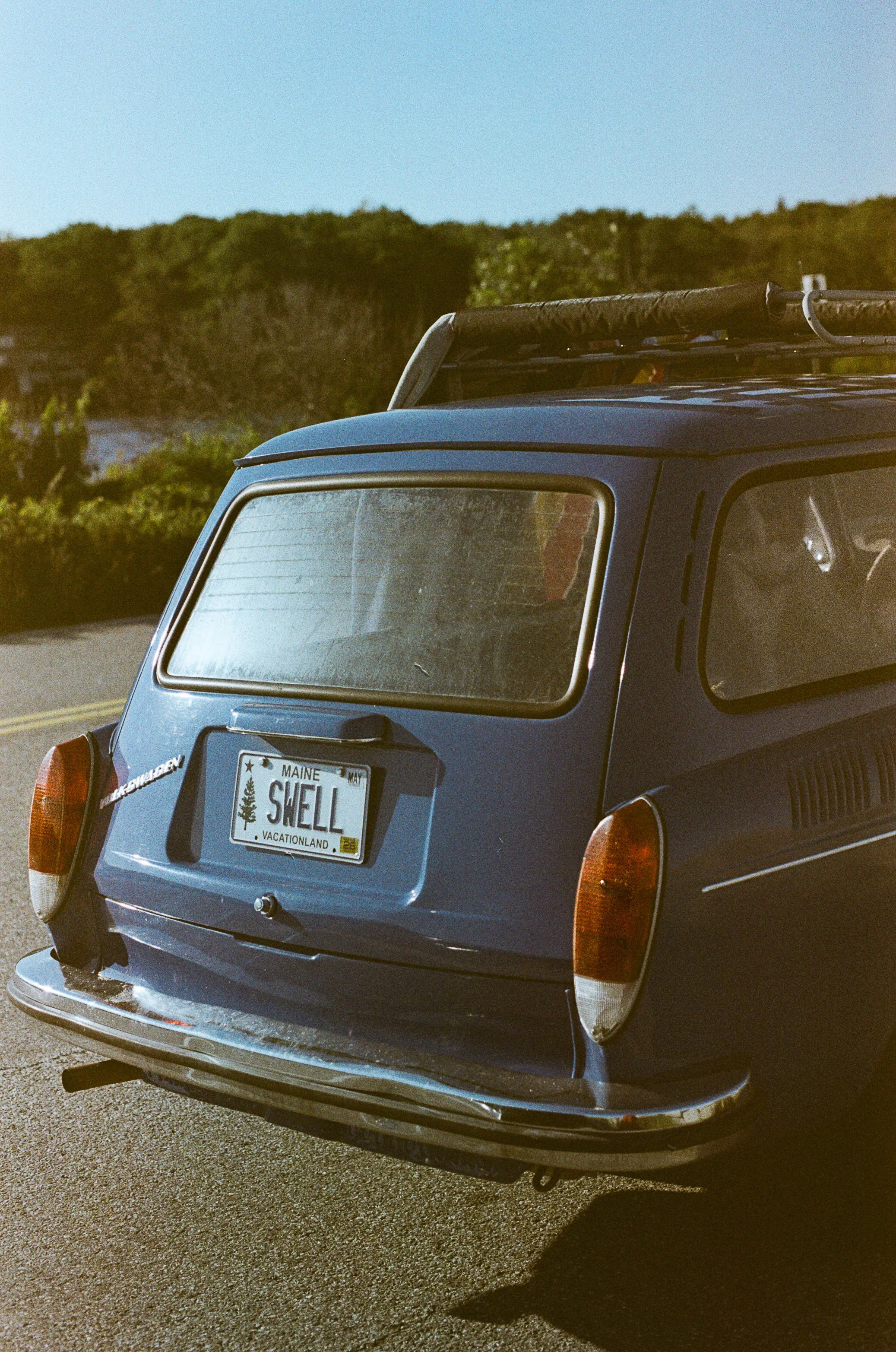 Close-up of the rear of a vintage blue Volkswagen Beetle with a Maine license plate reading 'SHELL'.