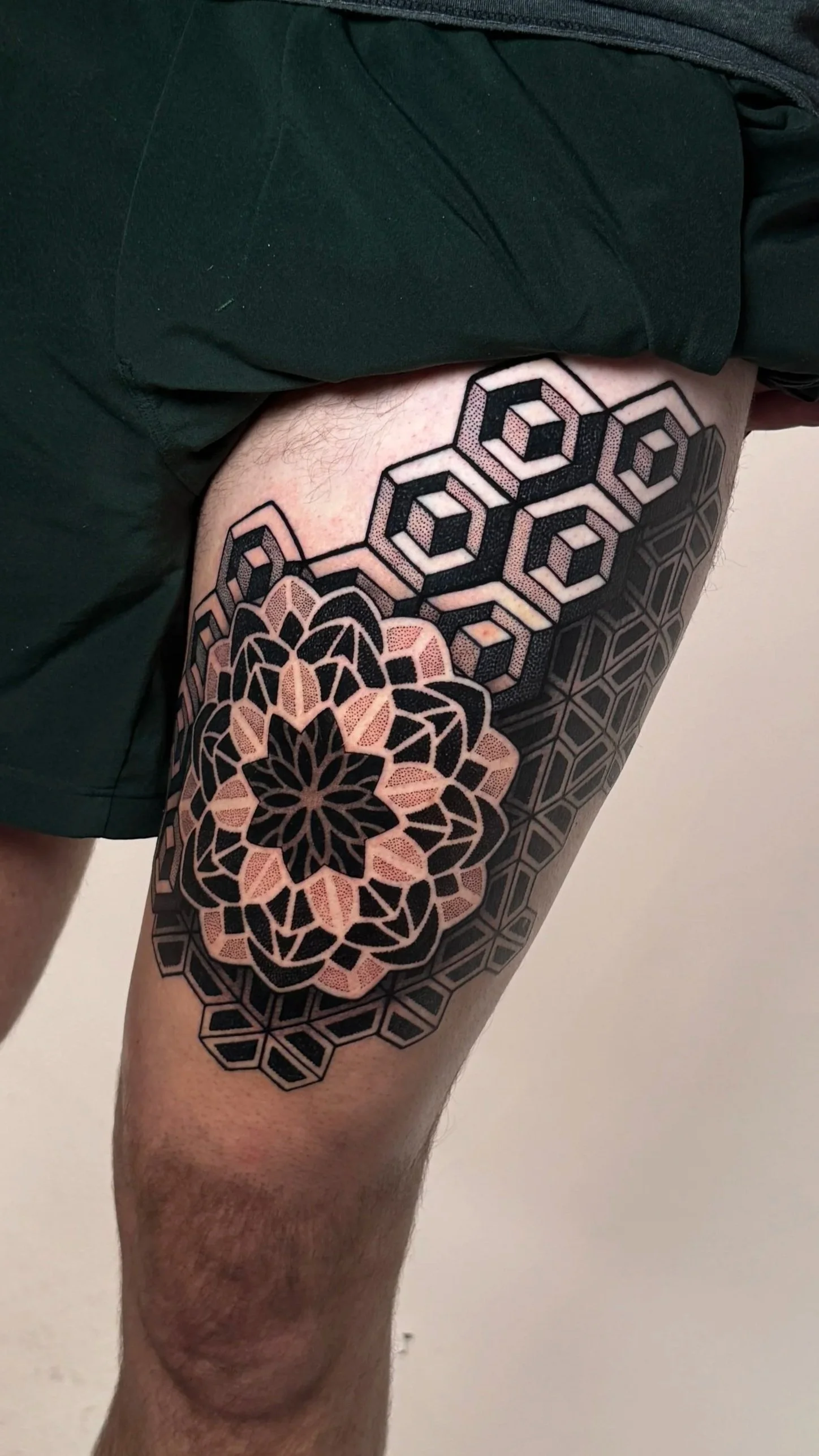 Tattooed thigh showing geometric patterns and a floral design with black and peach colors.