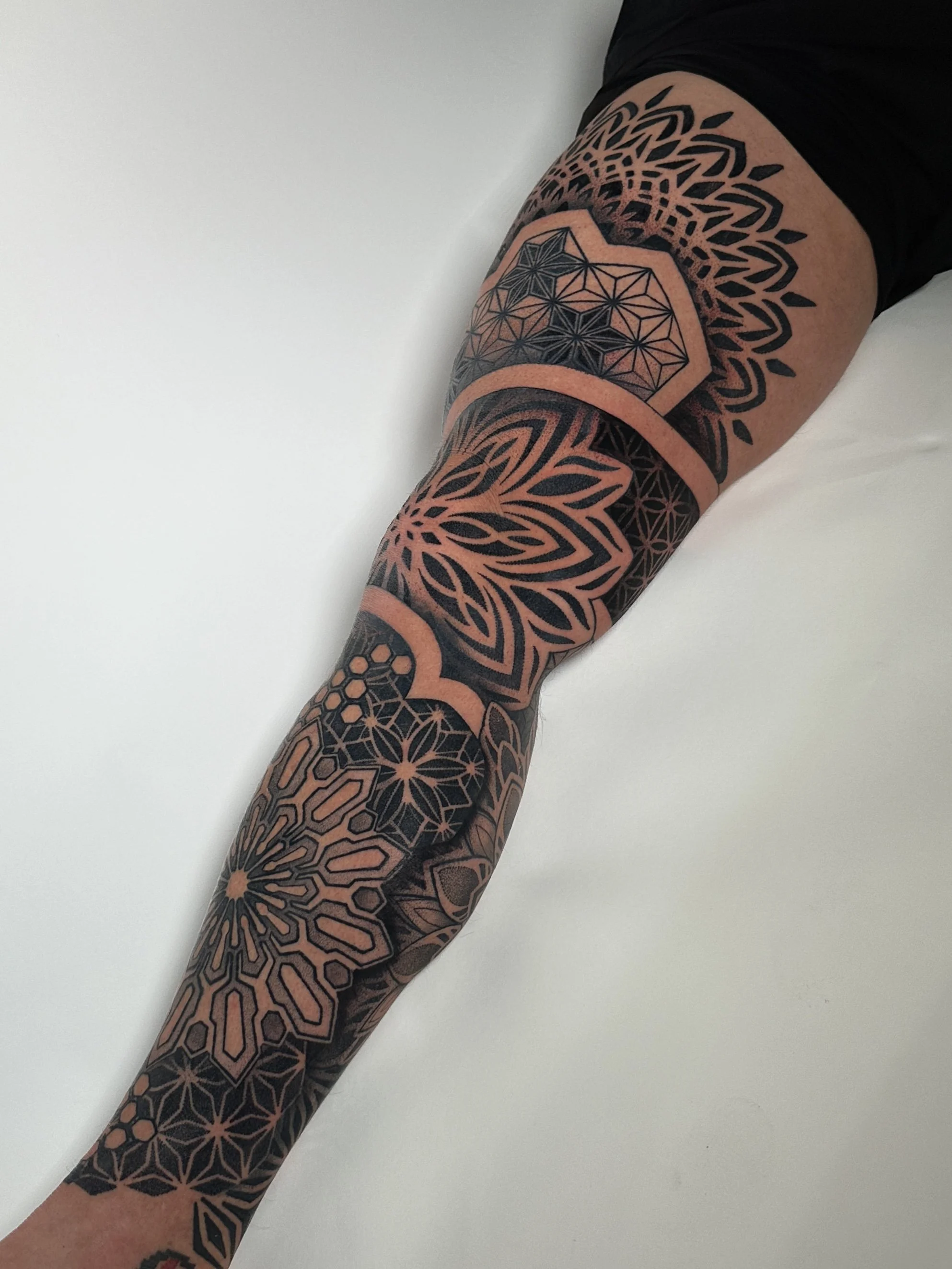 A person's arm with geometric tribal-style tattoos extending from the shoulder to the wrist.
