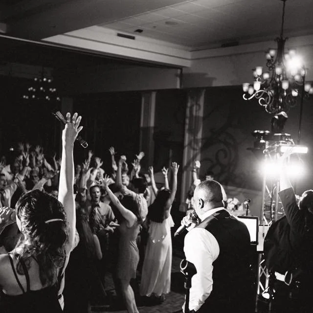 People dancing at a party with a DJ and lighting equipment.