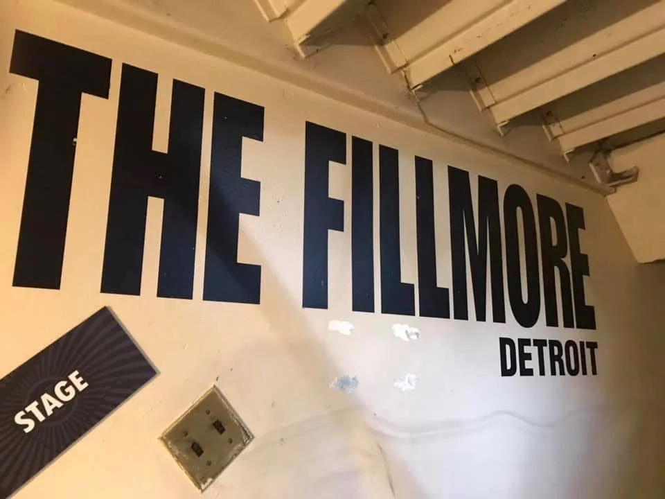 Wall with large black text reading "The Fillmore Detroit" and a smaller sign labeled "Stage" in the bottom left corner.