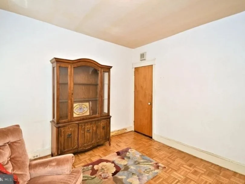 empty room with a wooden hutch, a upholstered chair, a small area rug, and a closed wooden door