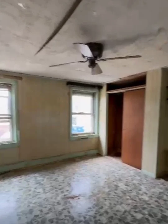 Empty room with two windows, a ceiling fan, and an open closet.