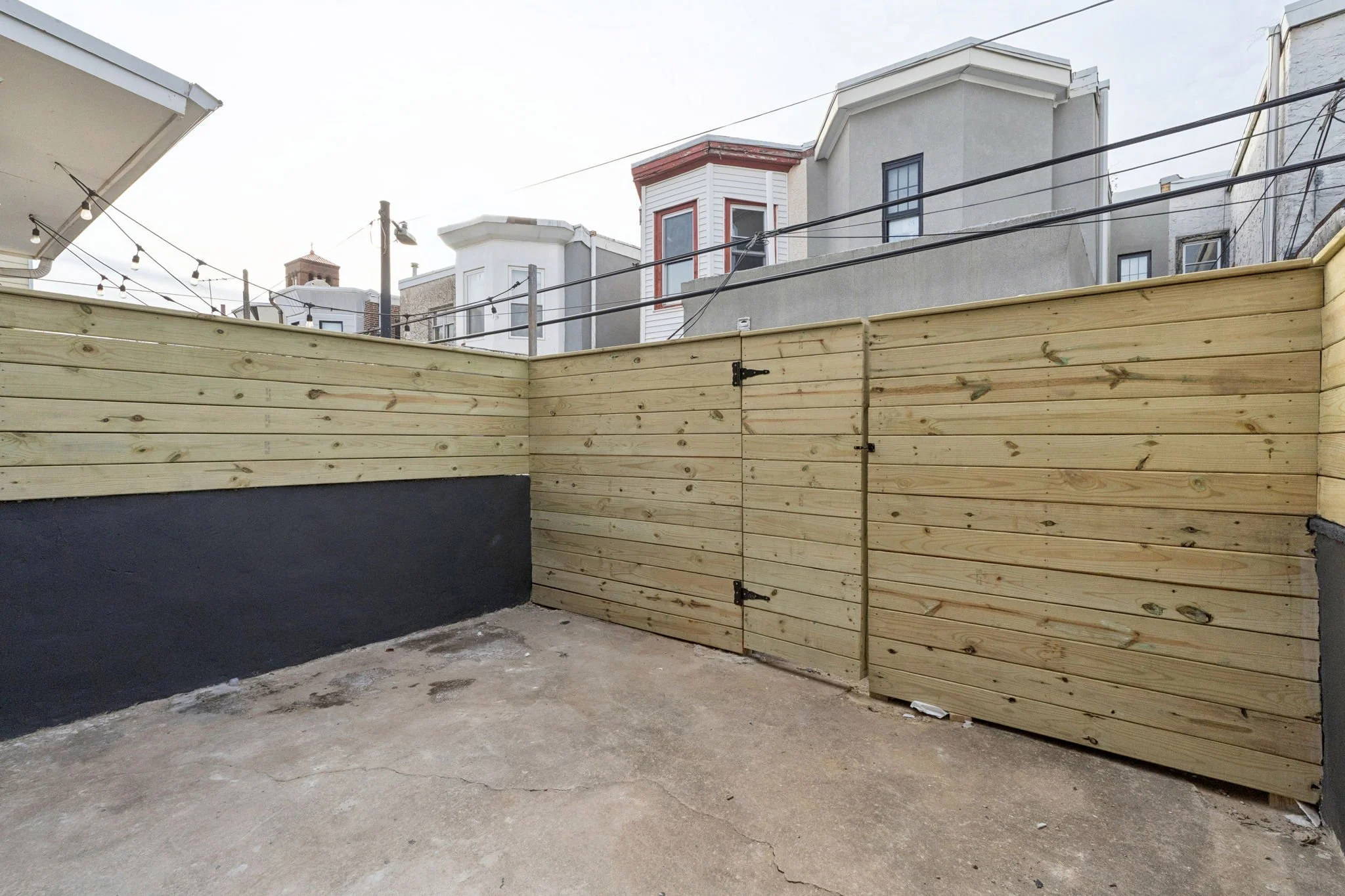 New wooden fence installed in backyard with neighboring houses in the background.